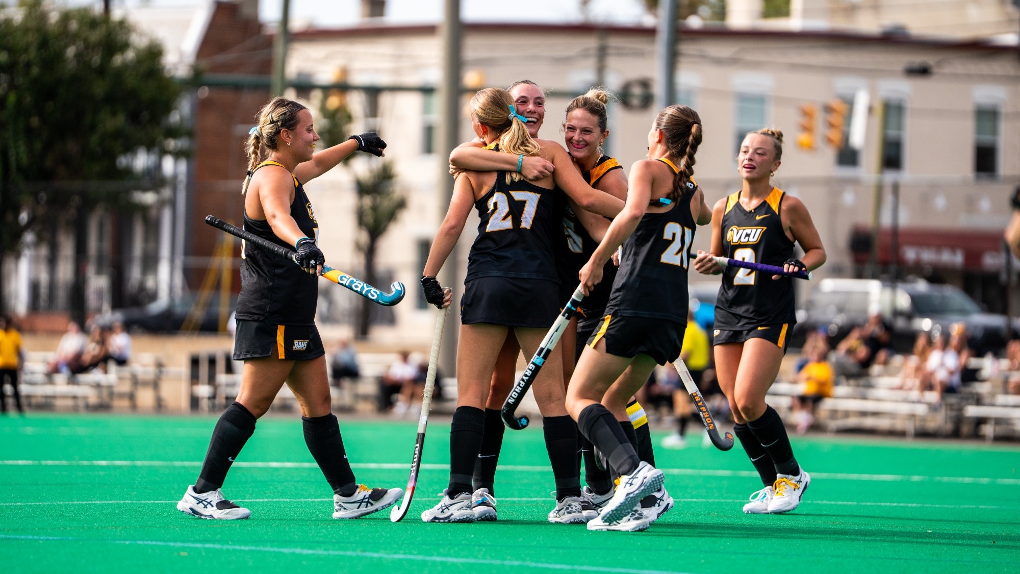 VCU Field Hockey Team celebrates a goal against Lock Haven hugging in celebration while wearing black uniforms