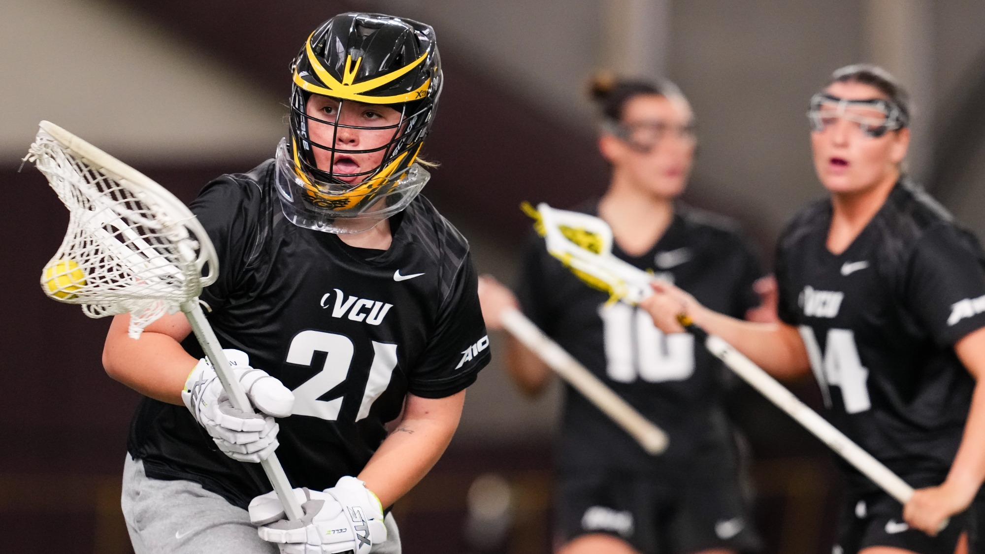 VCU Goalkeeper Lu Doyen wearing a black #21 jersey cradles the lacrosse ball in a game at Virginia Tech