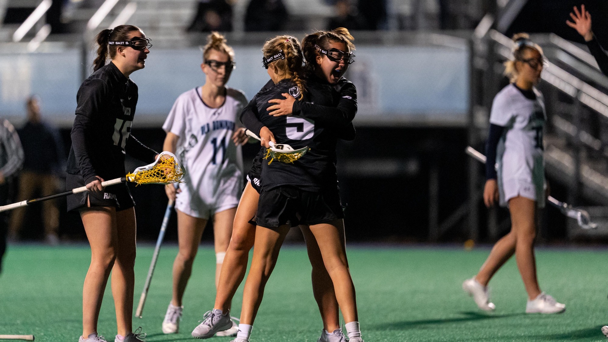 VCU Lacrosse's Rachel Koeneke wearing a black #5 jersey hugs her teammates after a goal against ODU
