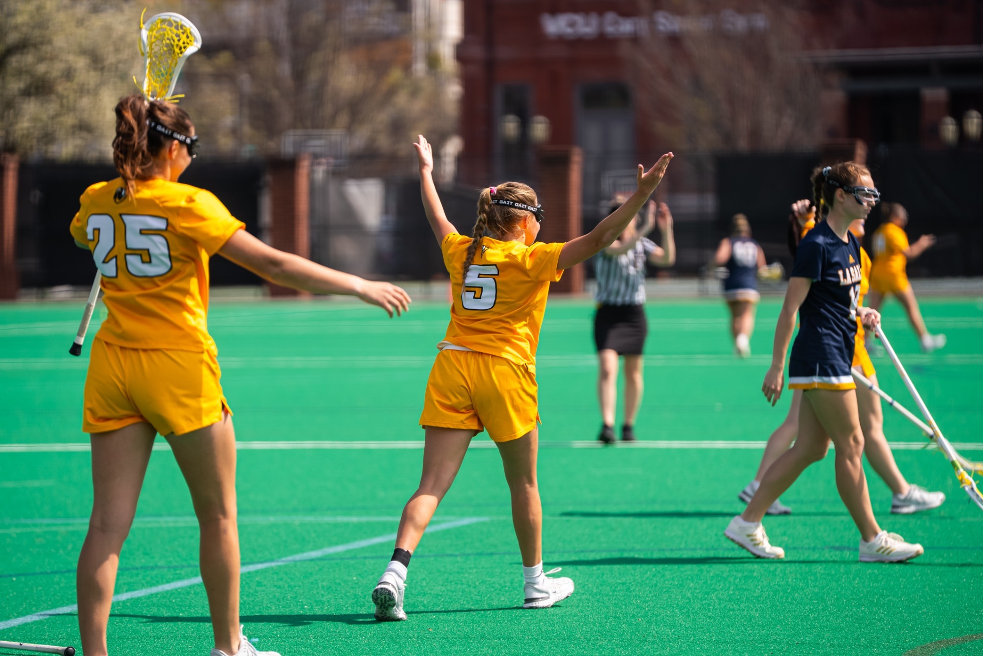 Rachel Koeneke of VCU lacrosse wearing a gold #5 jersey celebrates after scoring a goal in a game against La Salle