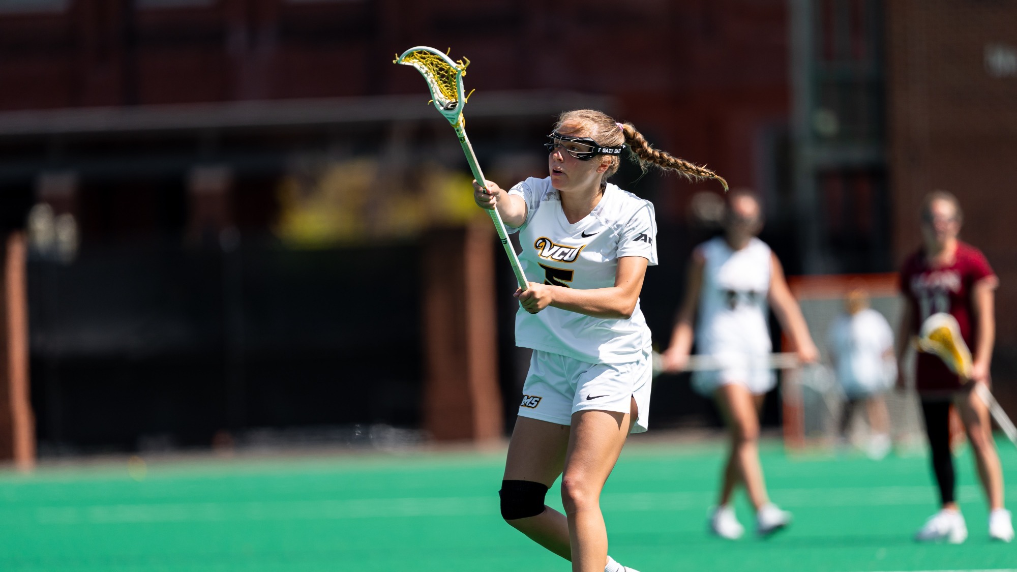Rachel Koeneke of VCU Lacorsse wearing a white #5 jersey passes the ball in a game against Elon