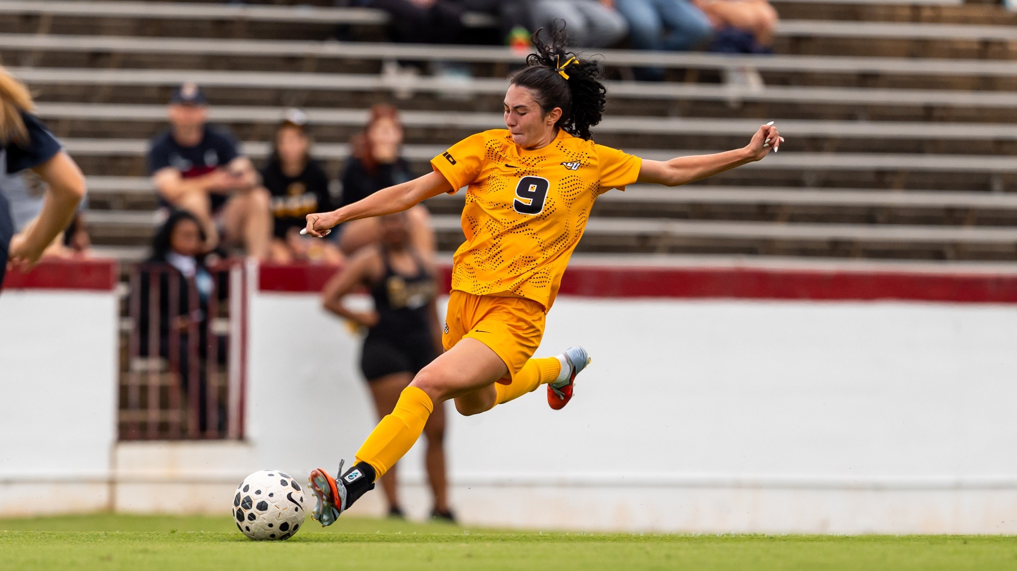 Brianna Lawrence kicks ball on senior day