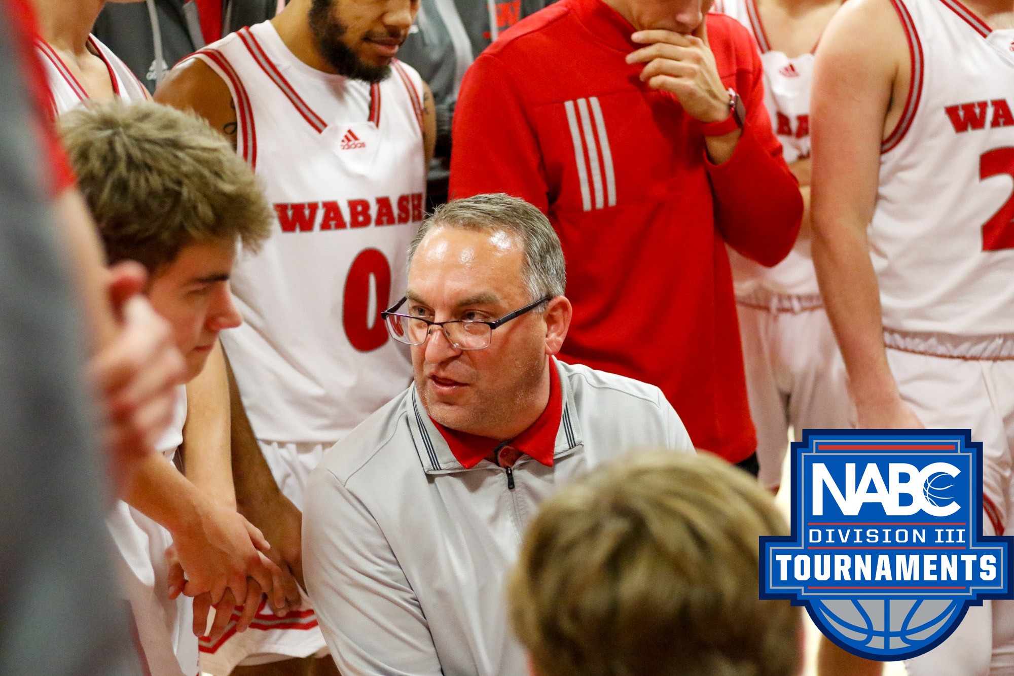 Wabash College head basketball coach Kyle Brumett with promotional logo for the NABC DIII Tournament