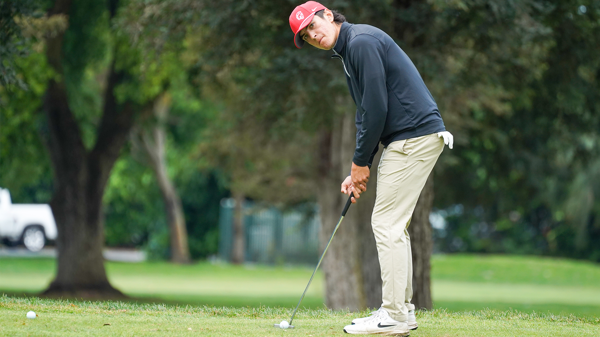 Owen Bascom lines up a putt on a golf green.