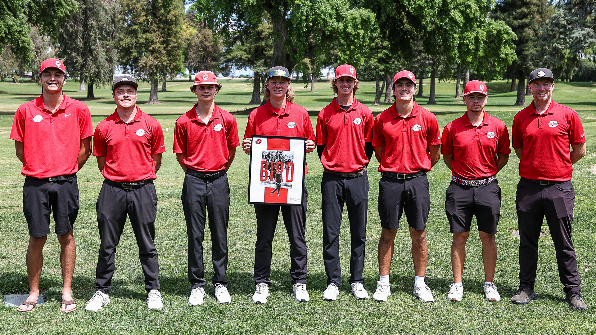 Stan State men’s golf team poses on the course during Senior Day as a player holds a poster honoring Chase Bird.