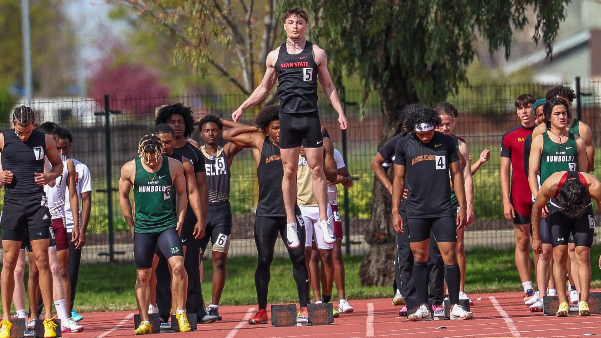 Photo of Stan State sprinter Blayne Siebert at the starting line alongside other athletes preparing for a race on the track.