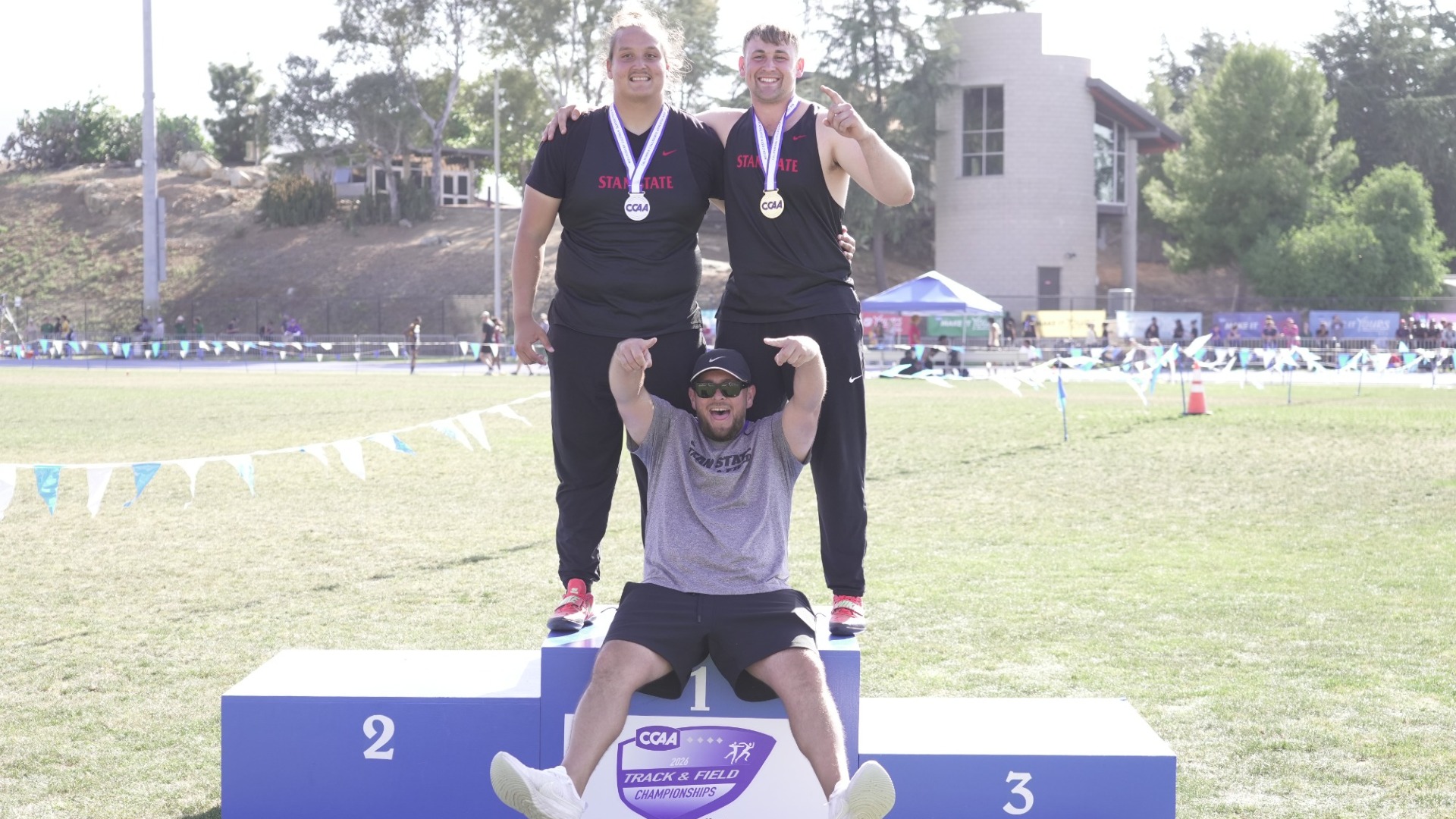 Luke Giannotta and Logan Edwards standing on the top step of the podium, while Casey Ballinger sits at the bottom, because they both just thre Hammer's 1000000 miles.