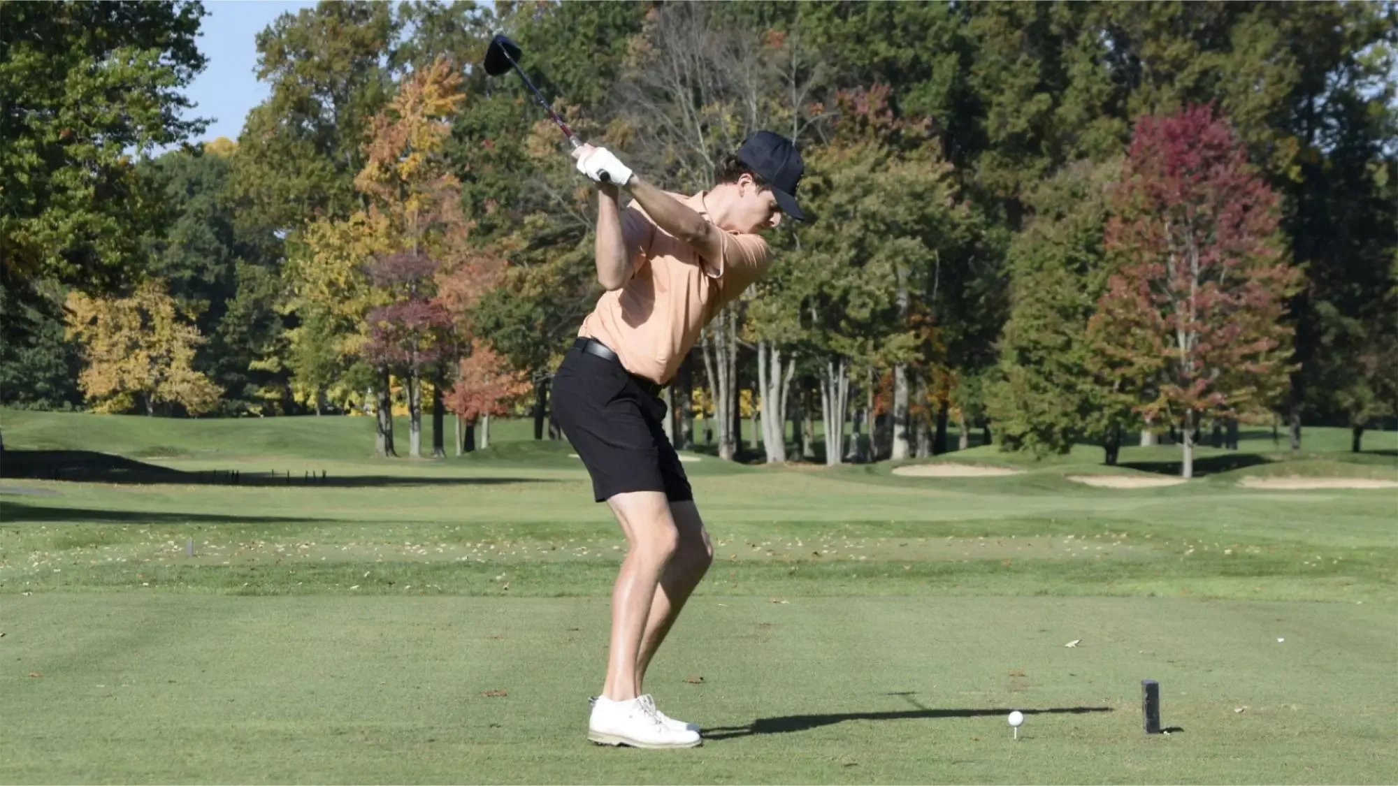 A Waynesburg golfer in an orange golf shirt tees off