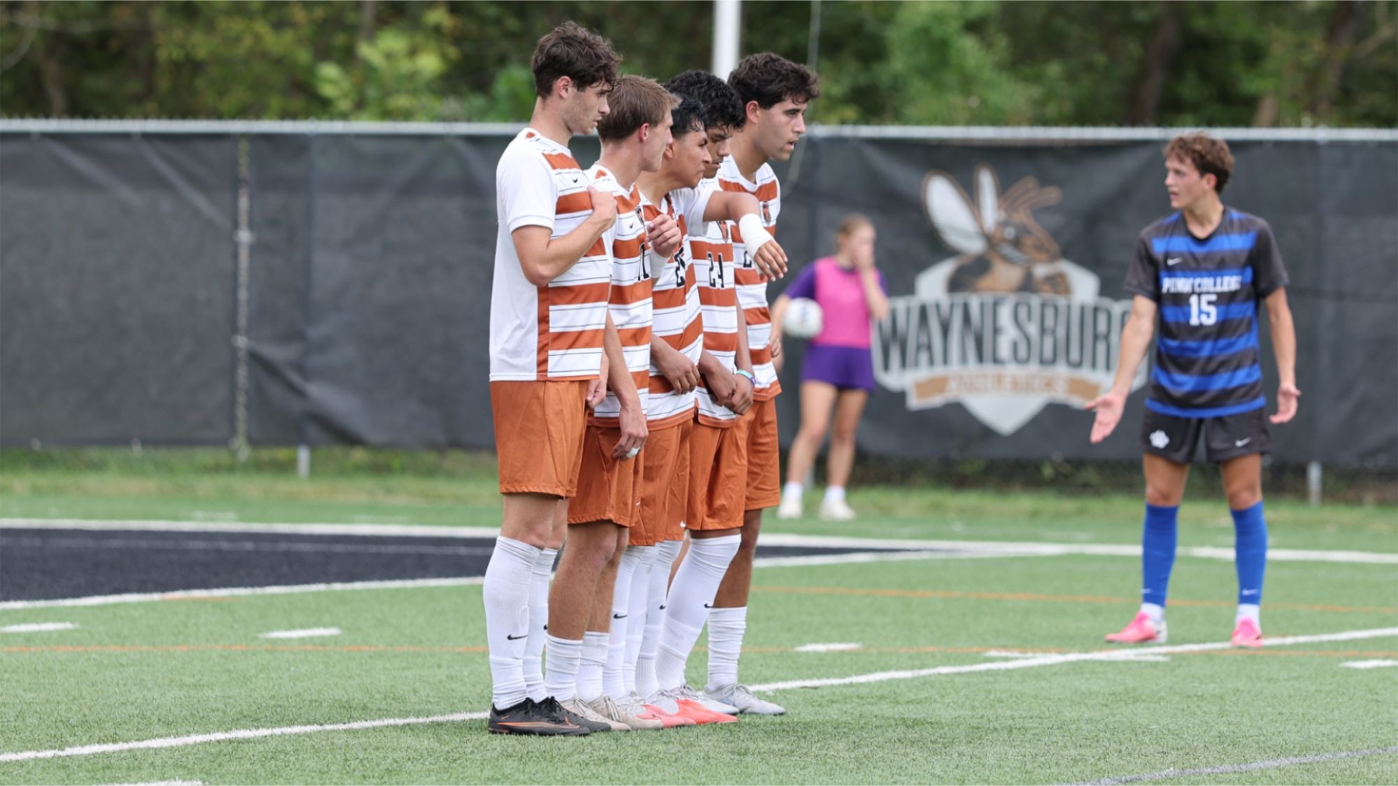 Four Waynesburg men's soccer players form a wall to attempt to block a free kick