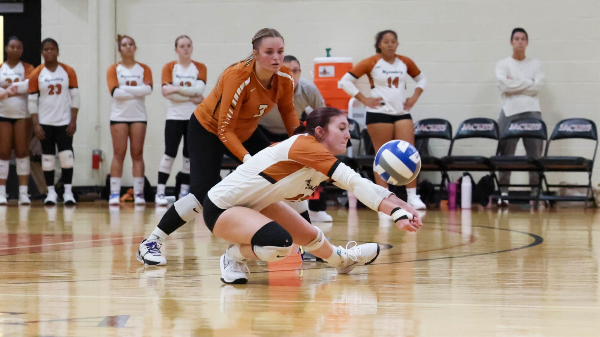 Shannon Zawislak drops down to a crouch to bump the volleyball as a teammate looks on in the background