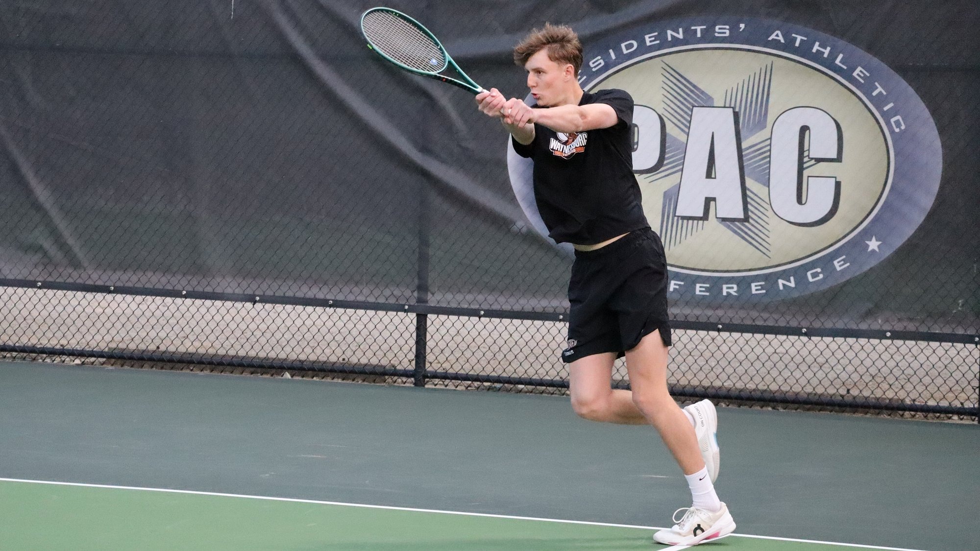 Waynesburg men's tennis player returns a volley