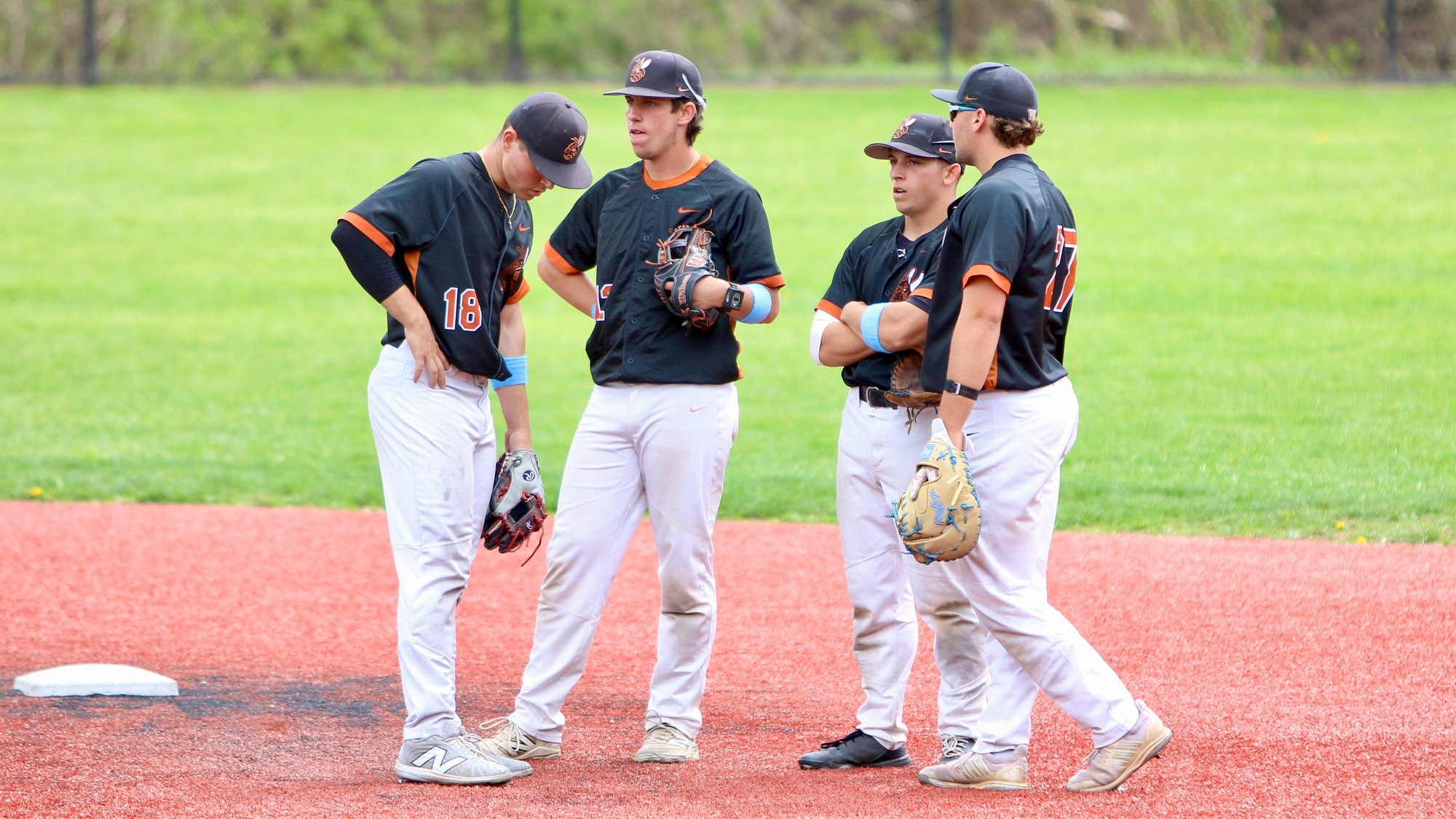 Four Waynesburg baseball players gather on the field