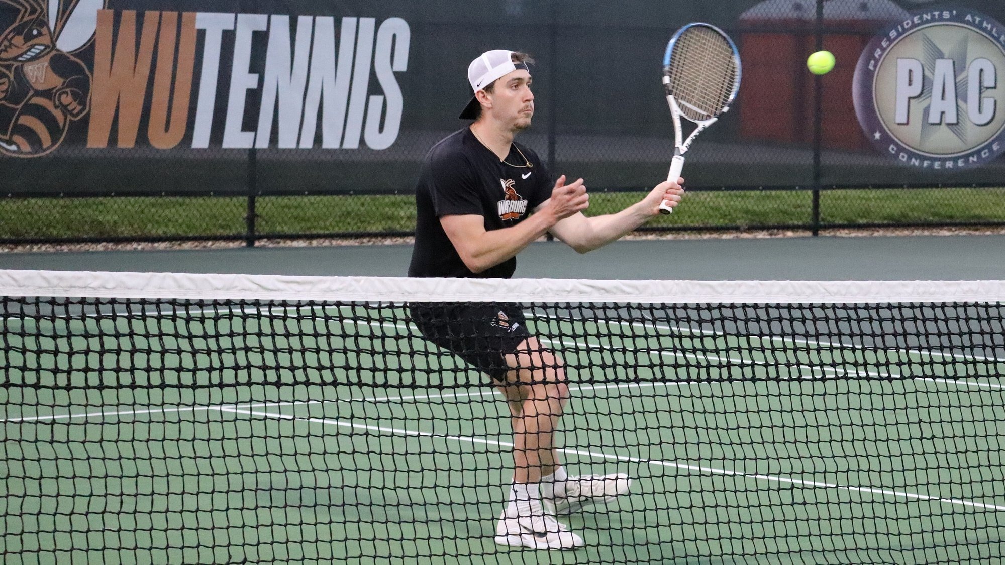 Waynesburg player volleys near the net