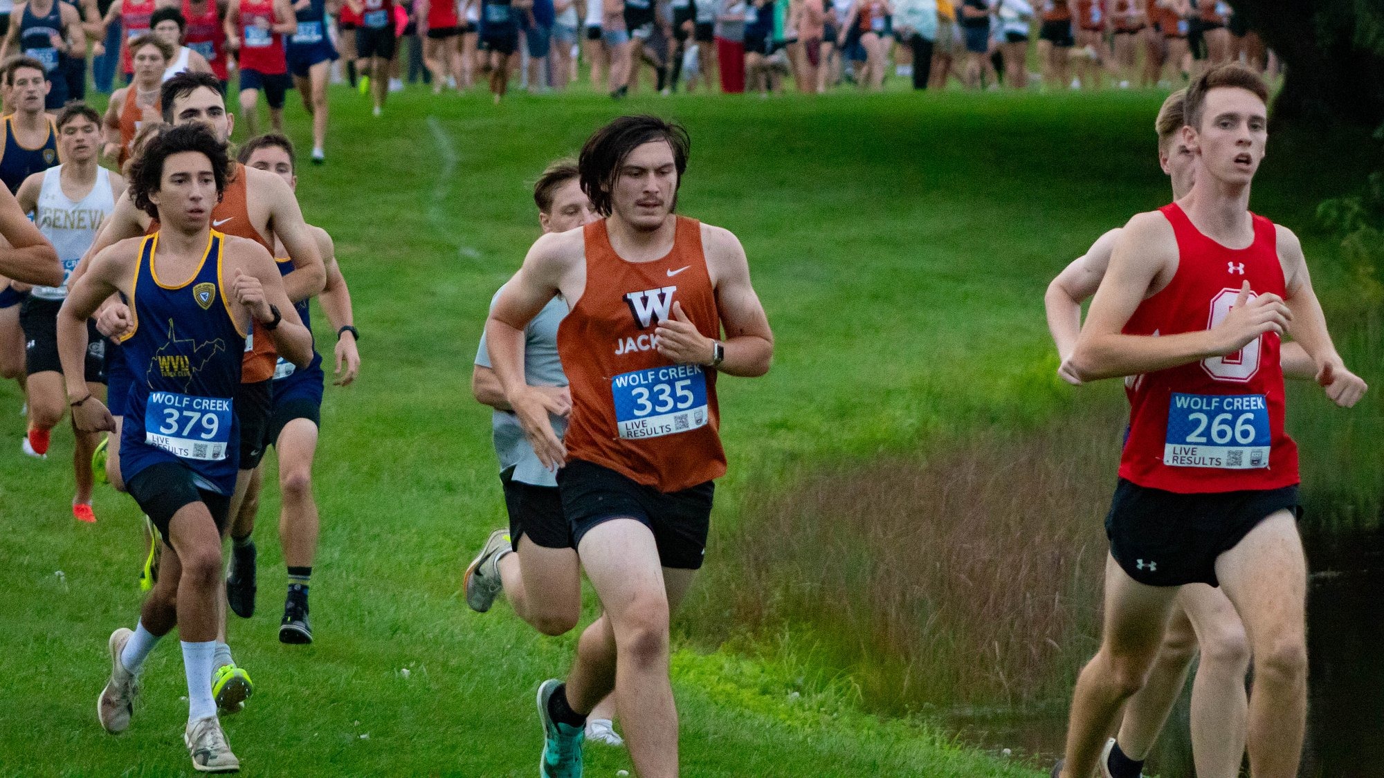 A group of men's cross country runners race around a bend in the course