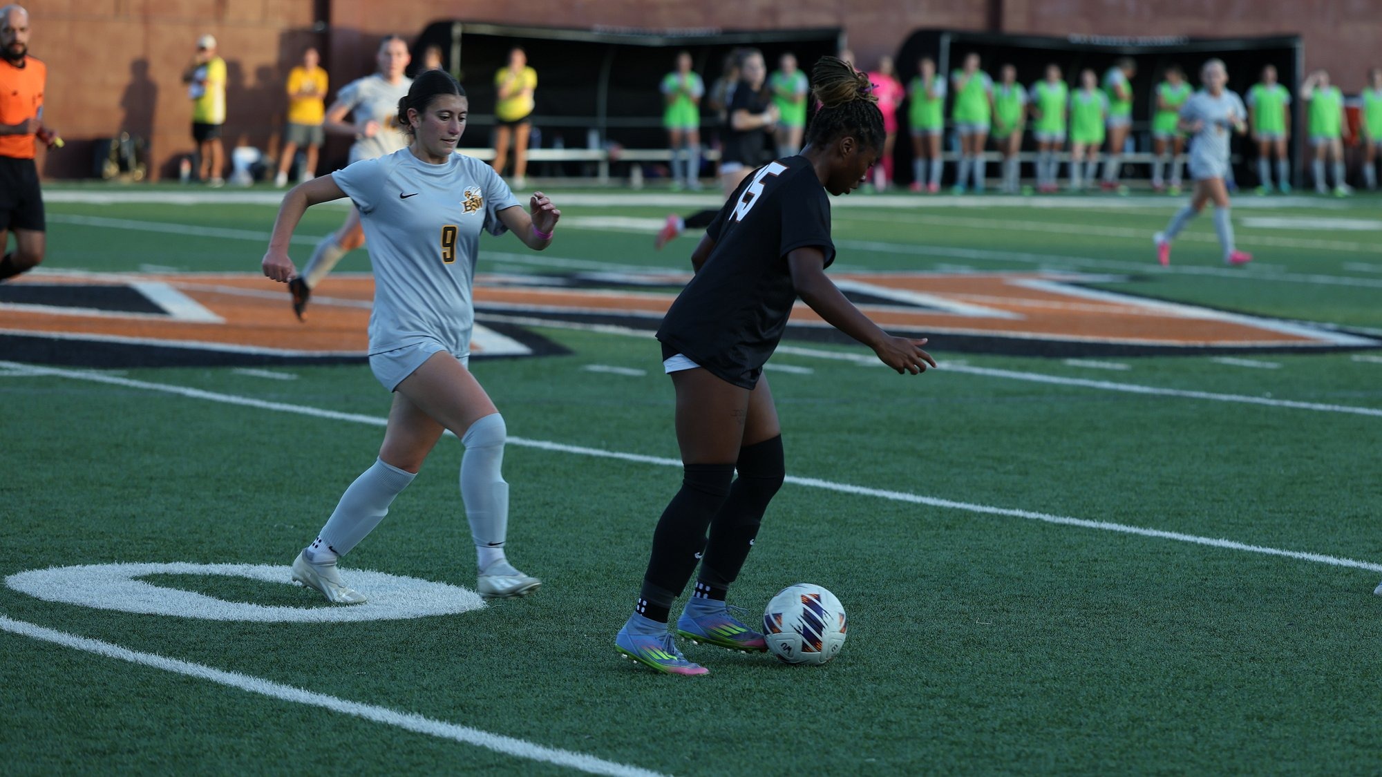 Waynesburg's Miracle Hershey, wearing an all black uniform with white numbers, dribbles the ball away from a Baldwin Wallace defender