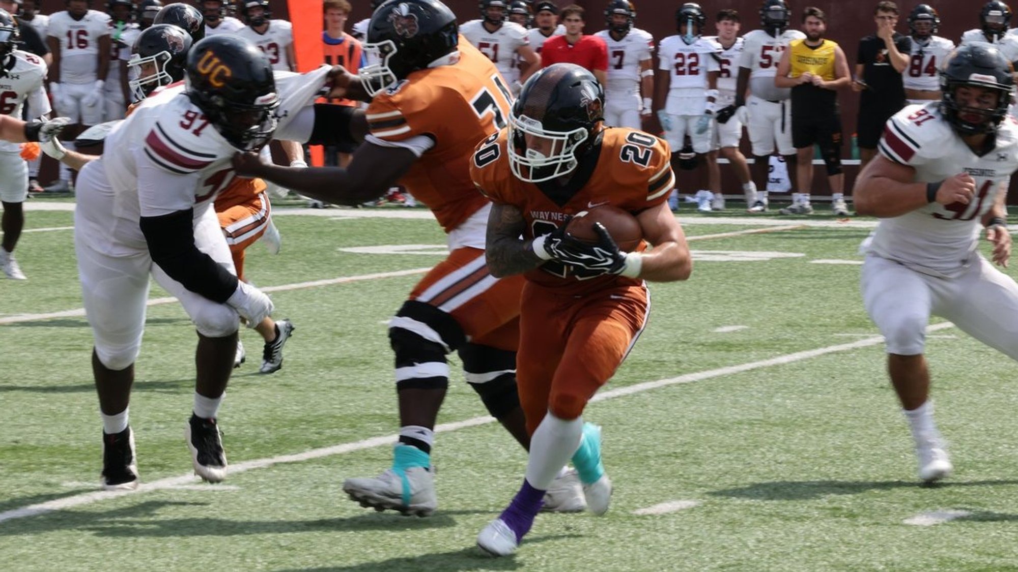 Running back Zayne Cawley holds onto the football with two hands as he looks for running room against a line of defenders