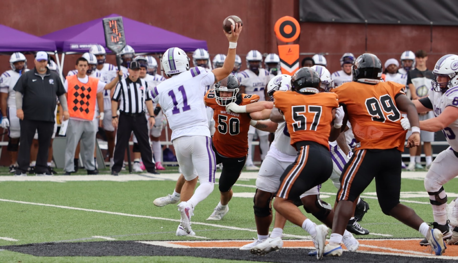 Waynesburg's Tyler Curry, wearing his number 50 orange jersey, attempts to sack the Capital quarterback