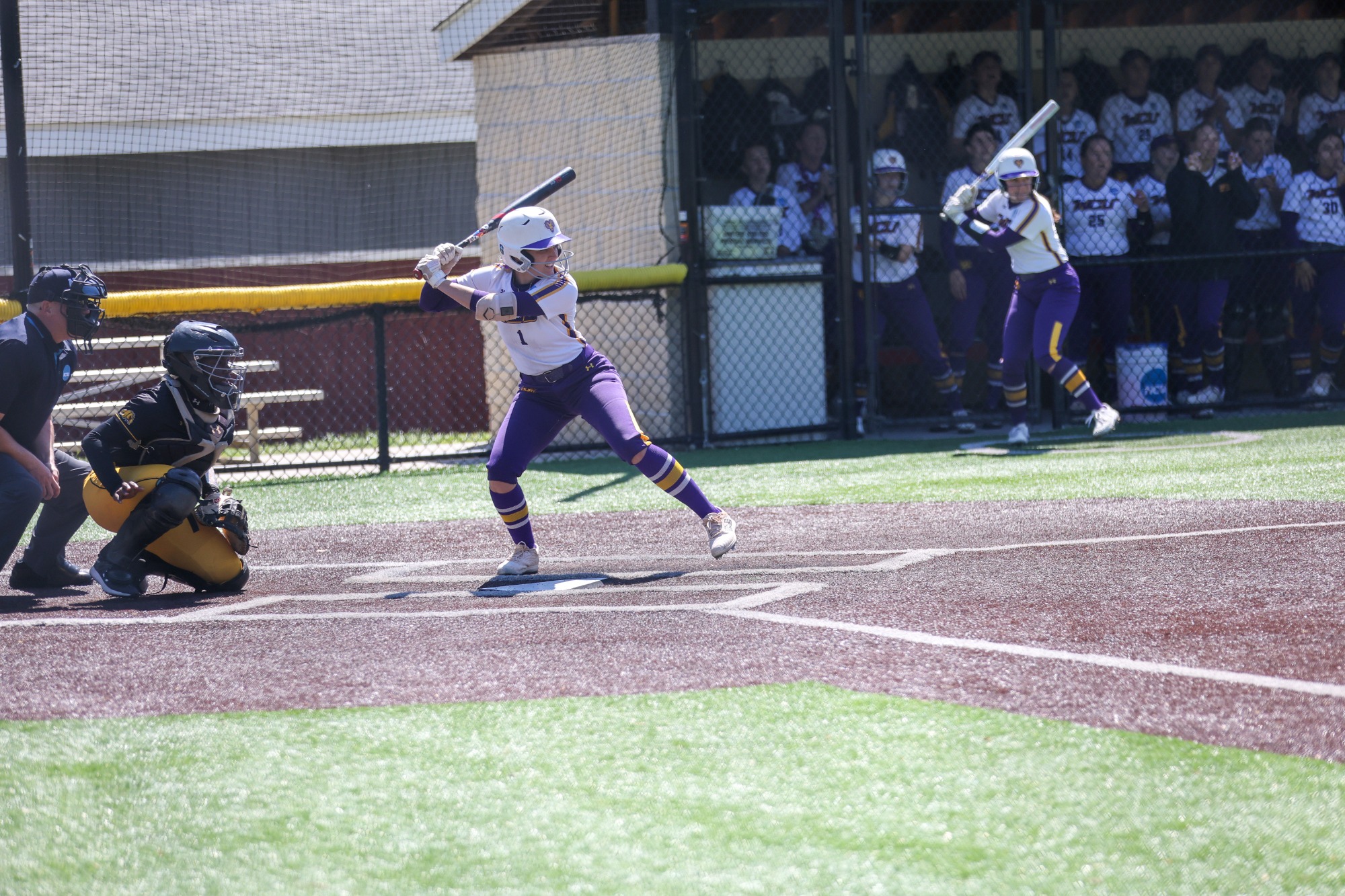 NUMBER 1 HITTING MID PITCH  IN TEAM ISSUED WHITE UNIFORM AND PURPLE PANTS 
