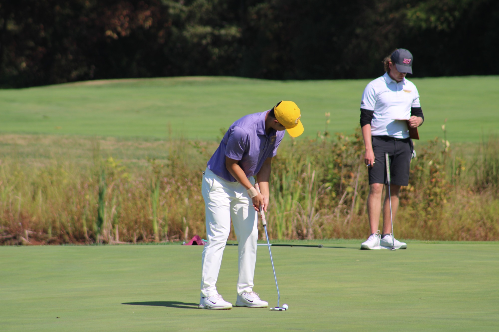 Kimura PUTTING ON GREEN IN TEAM ISSUED YELLOW HAT, PURPLE SHIRT, AND WHITE PANTS