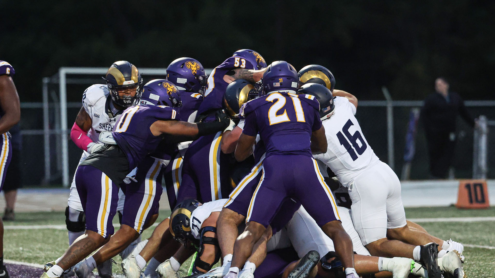 WCU Defense holds up Shepherd in a goal line stand with five defenders dressed in the home purple jerseys and purple pants