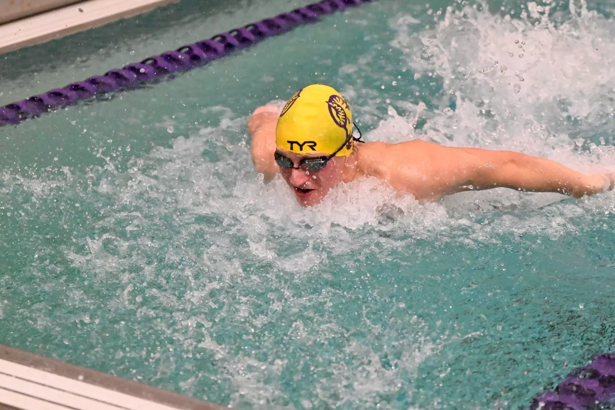 Austin Fastrich doing the individual medley for the Golden Rams with his TYR swim cap and goggles on.