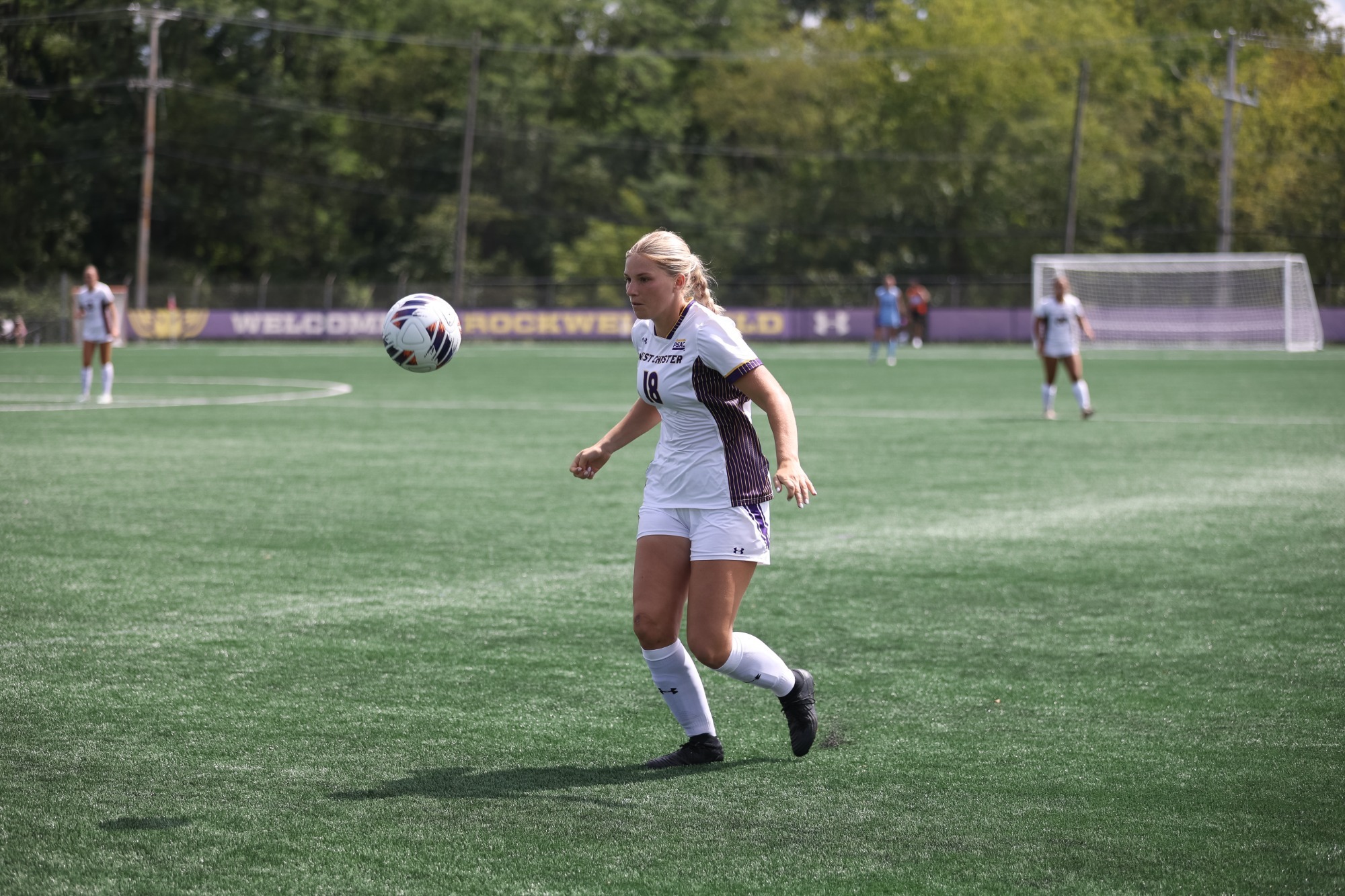 Sarah Roesing wearing home white uniforms chasing down a bouncing ball vs lackawanna