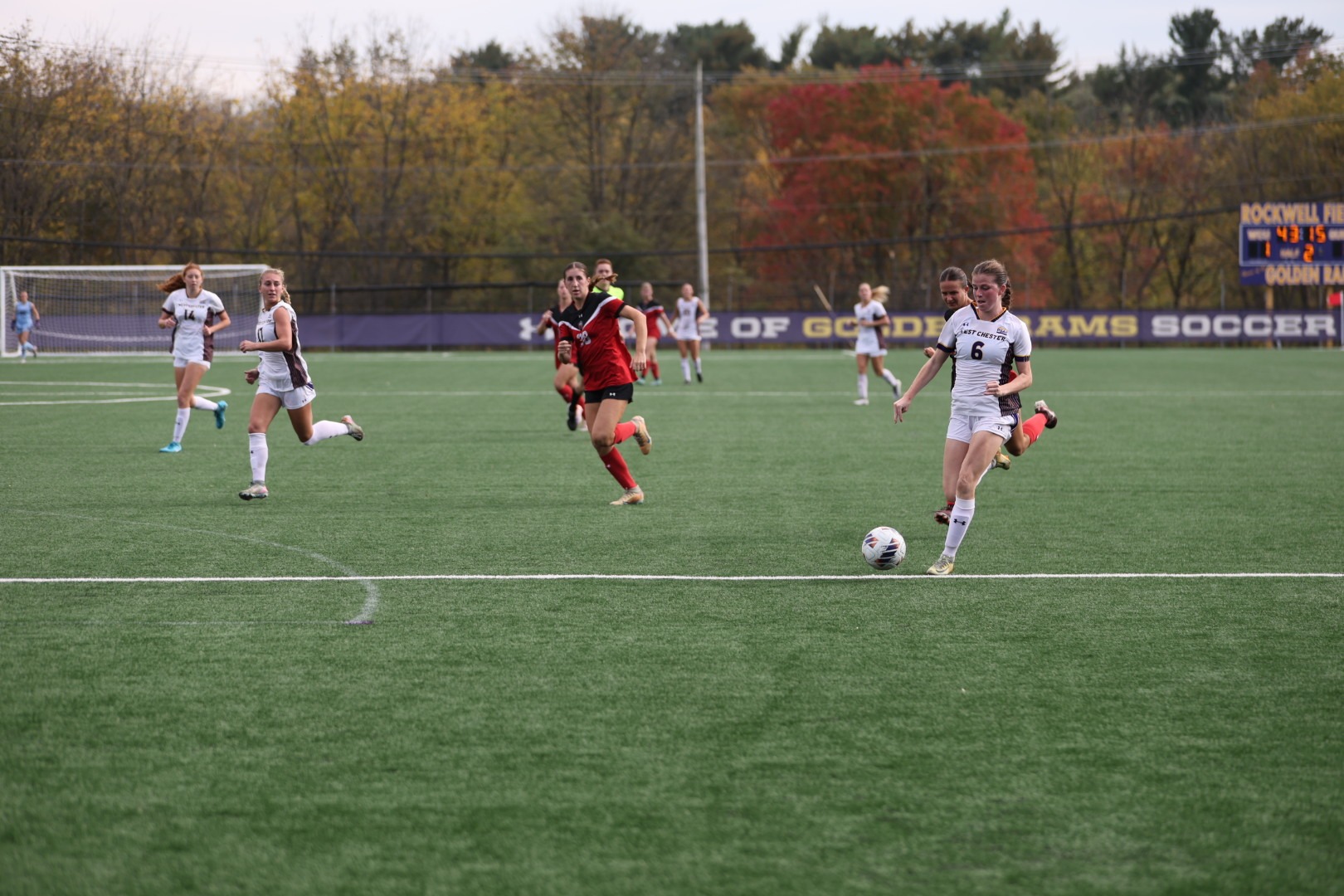 Kara Slavin wearing home white uniform with purple numbers carries the ball into the box vs ESU