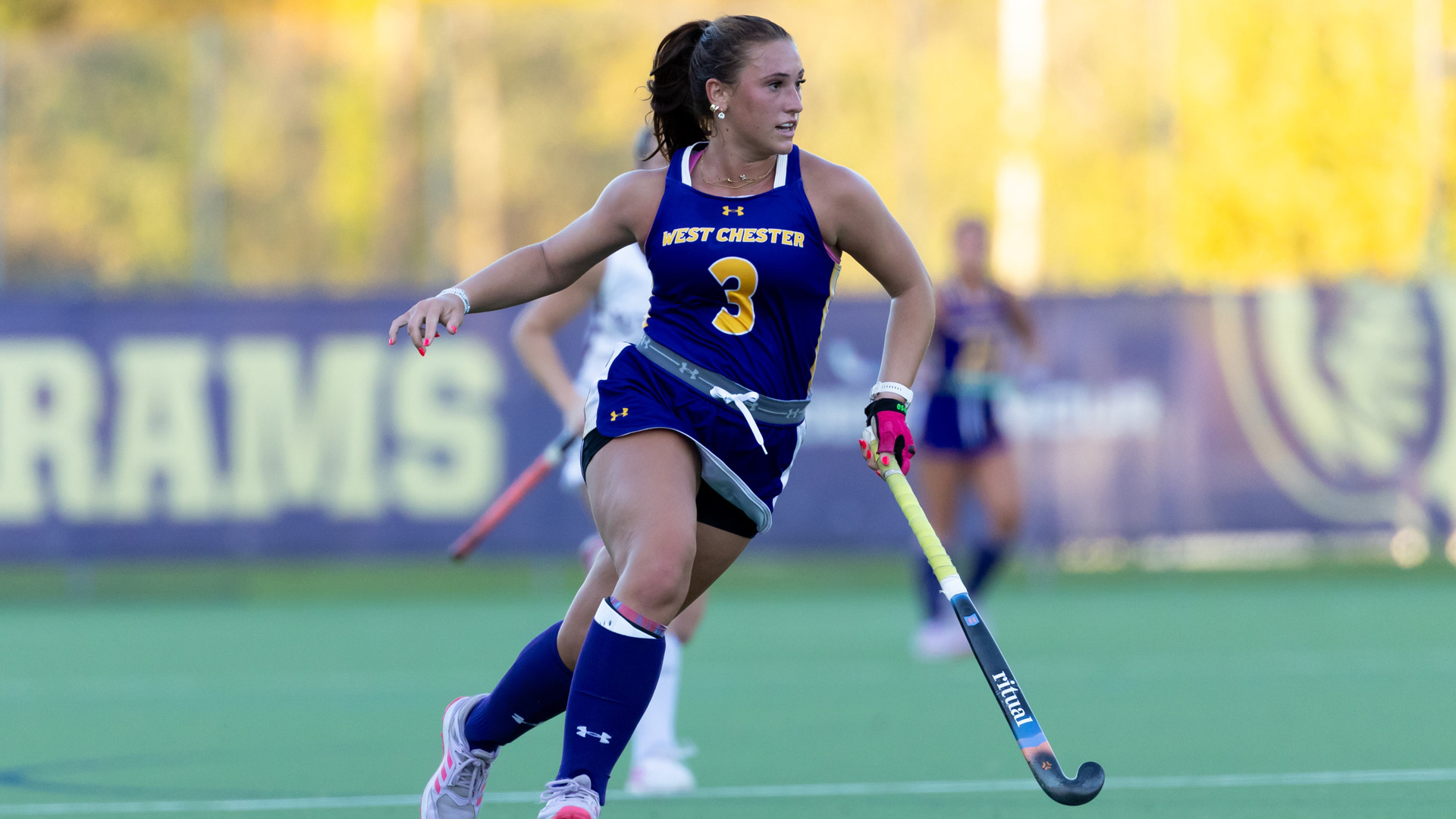 Anna Finn runs up field at home in her purple jersey with yellow numbers and writing