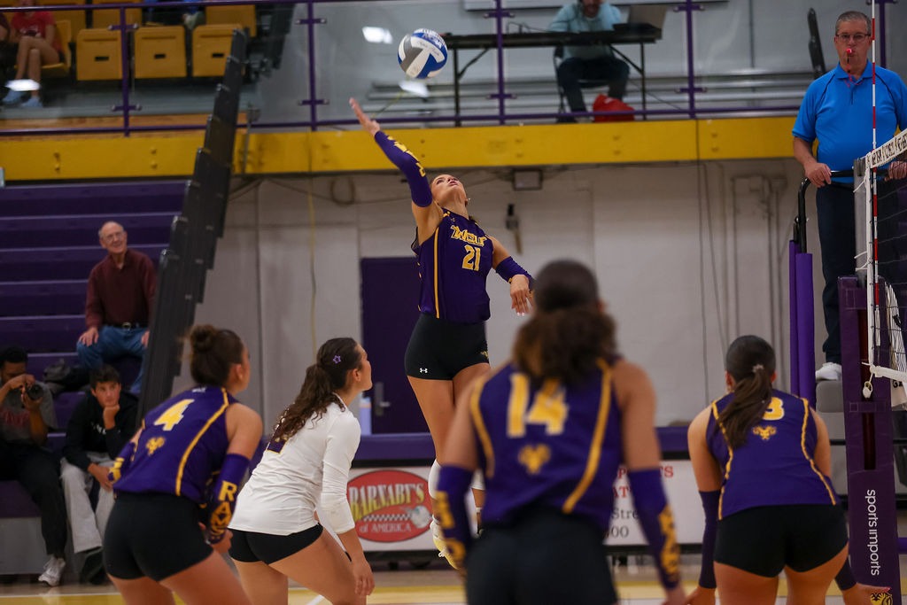 MAEVE GALLAGHER WEARING PURPLE SLEEVELESS TOP WITH GOLD STRIPE AND GOLD NUMBERS/WCU CIPHER ON CHEST REACHING BACK FOR A KILL AGAINST LACKAWANNA