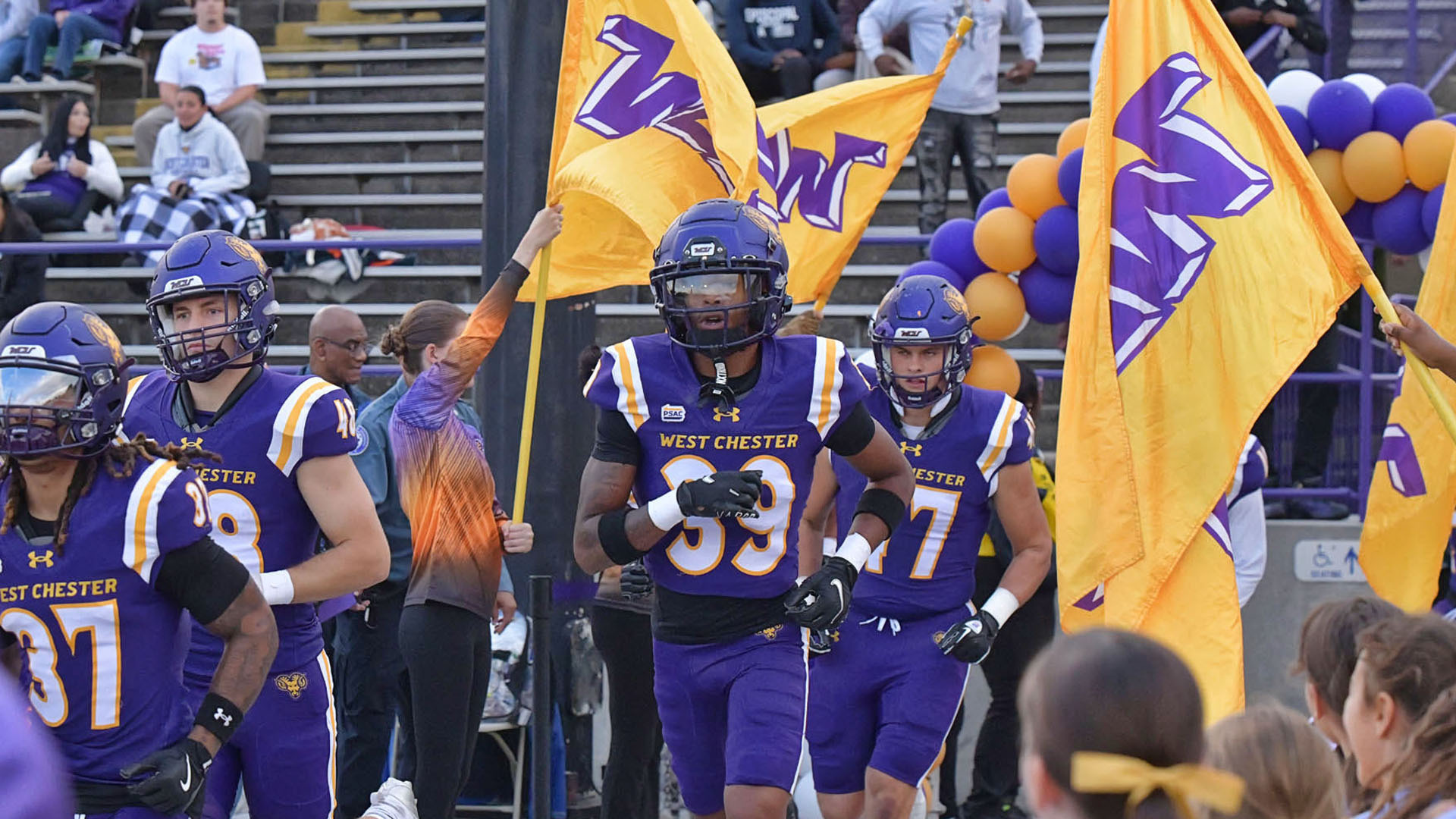 Football team running on the field in between flags