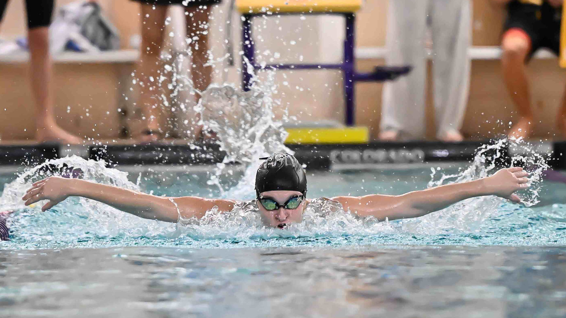 Danielle Hinkson swims the butterfly in her black tech women's swim suit with black swim cap