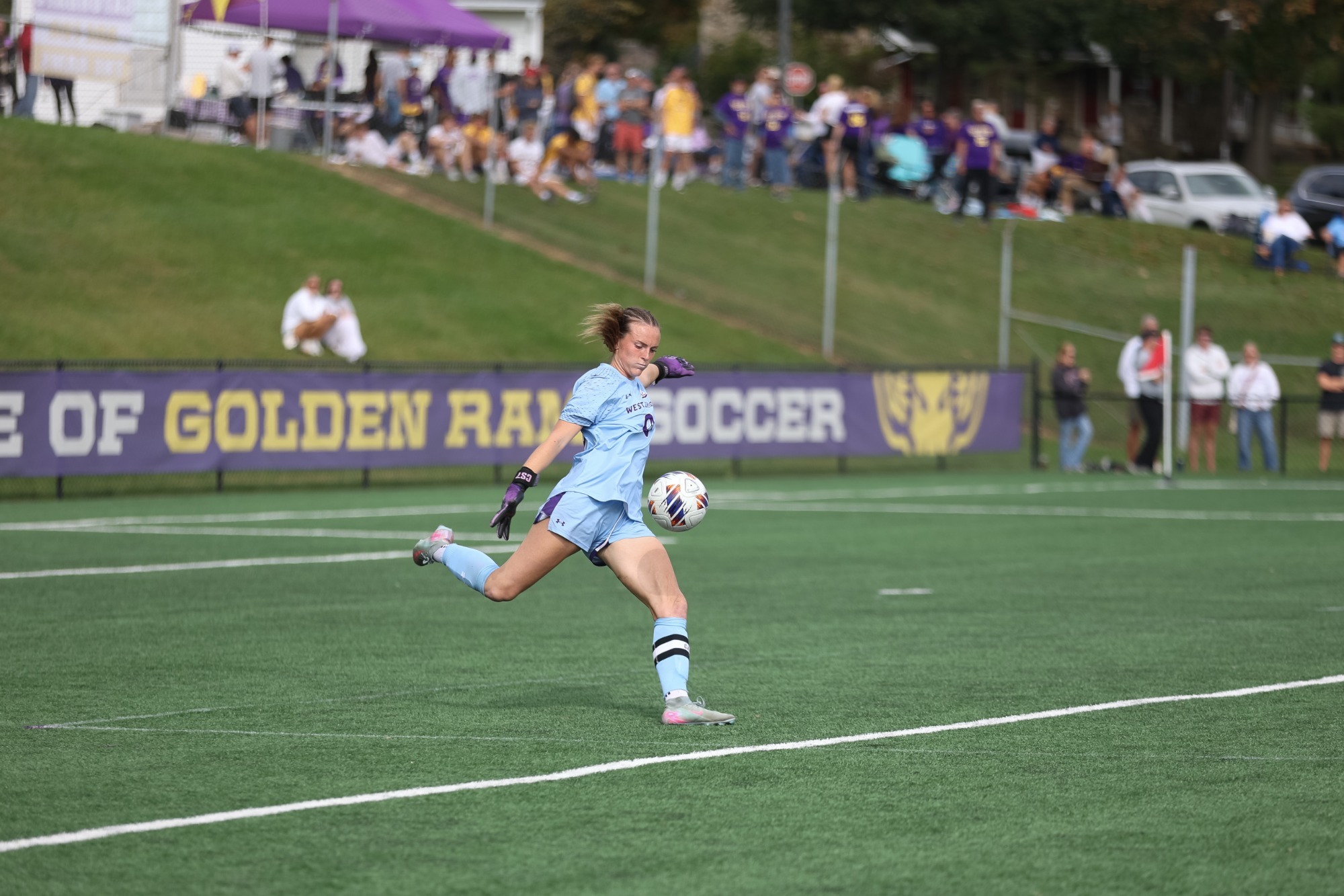Grace Keen wearing carolina blue goalkeeper kit punting vs Bloomsburg on Saturday afternoon on Rockwell Field