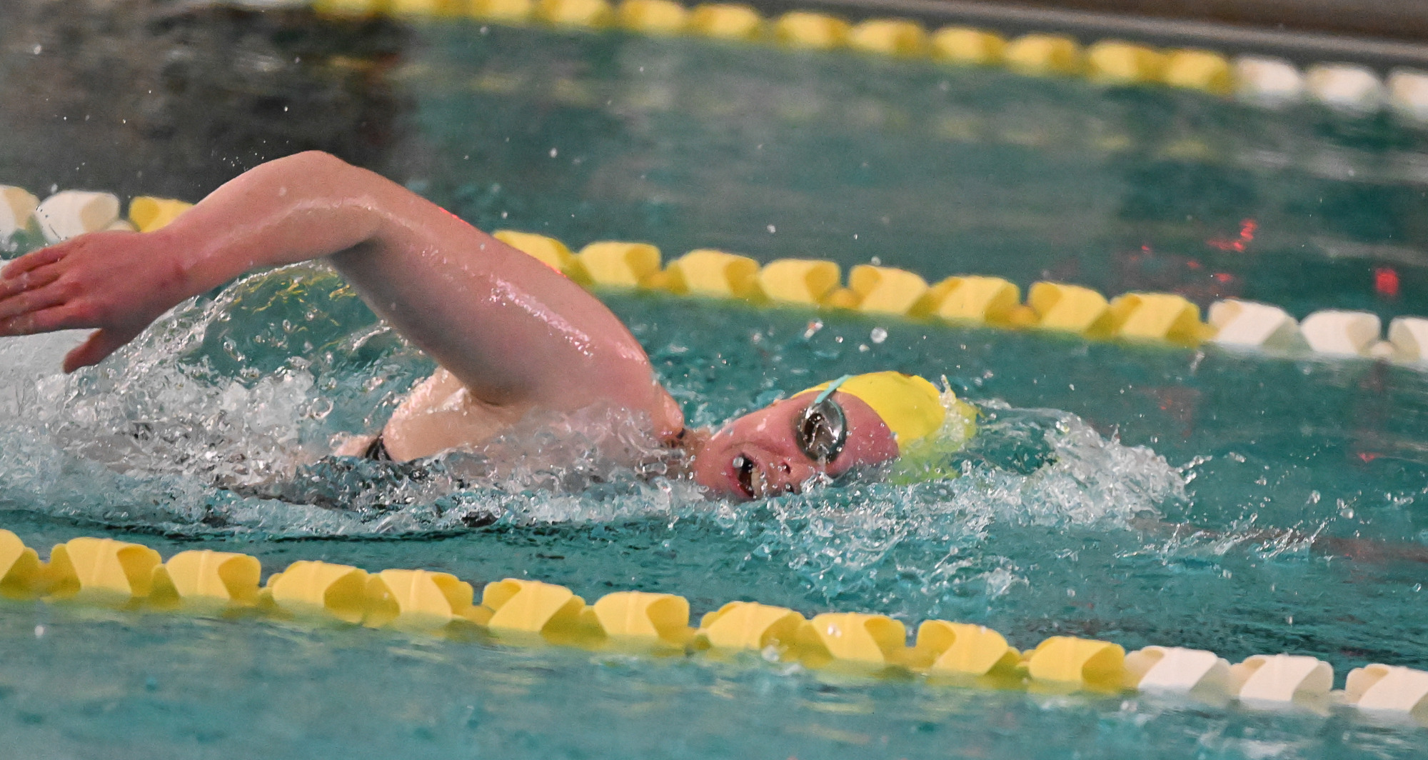 Greta Saville swims a distant event in team issued black swim suit and yellow TYR cap