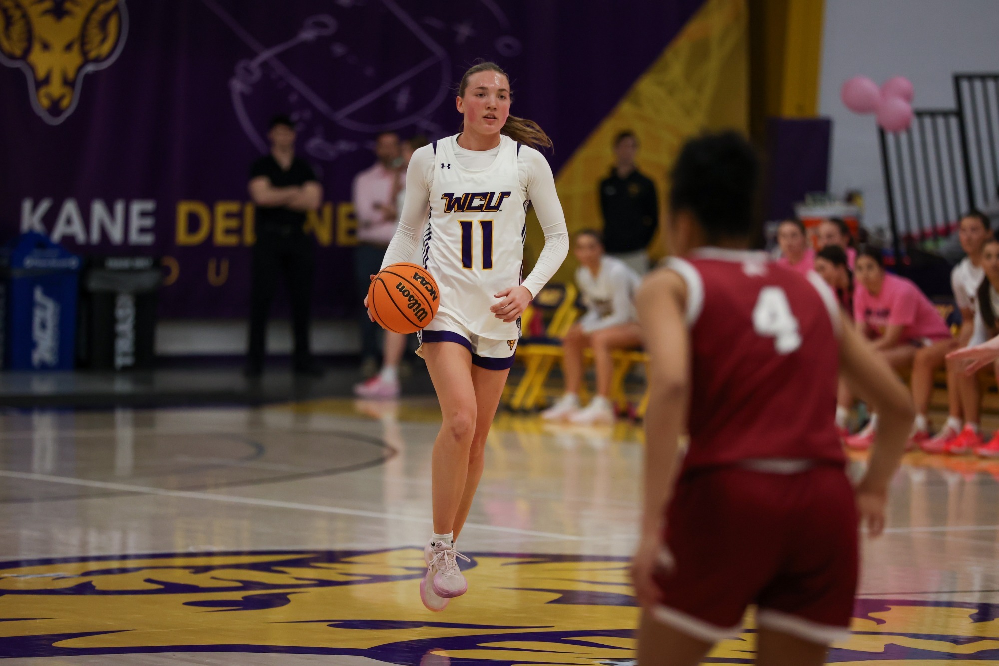 Lena Stein wearing team issued white uniform carries the ball up vs Lock Haven