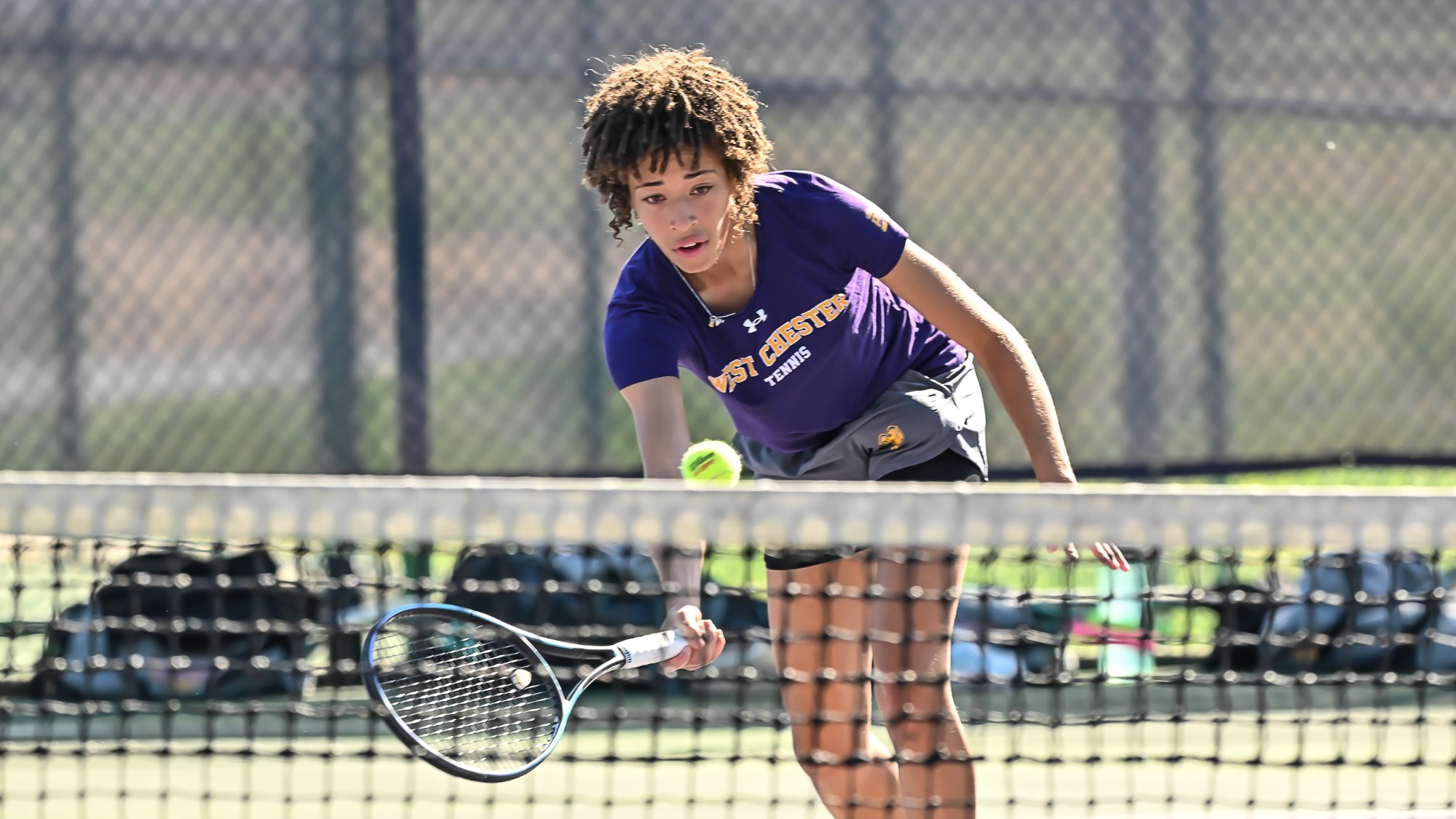 Ashleigh Grooms playing in purple top and gray shorts in women's tennis action vs St. Thomas Aquinas in fall season