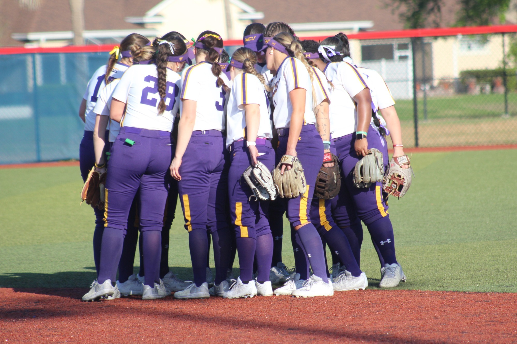 SB TEAM HUDDLE in white uniform with purple pants on field in florida on 3-10-26