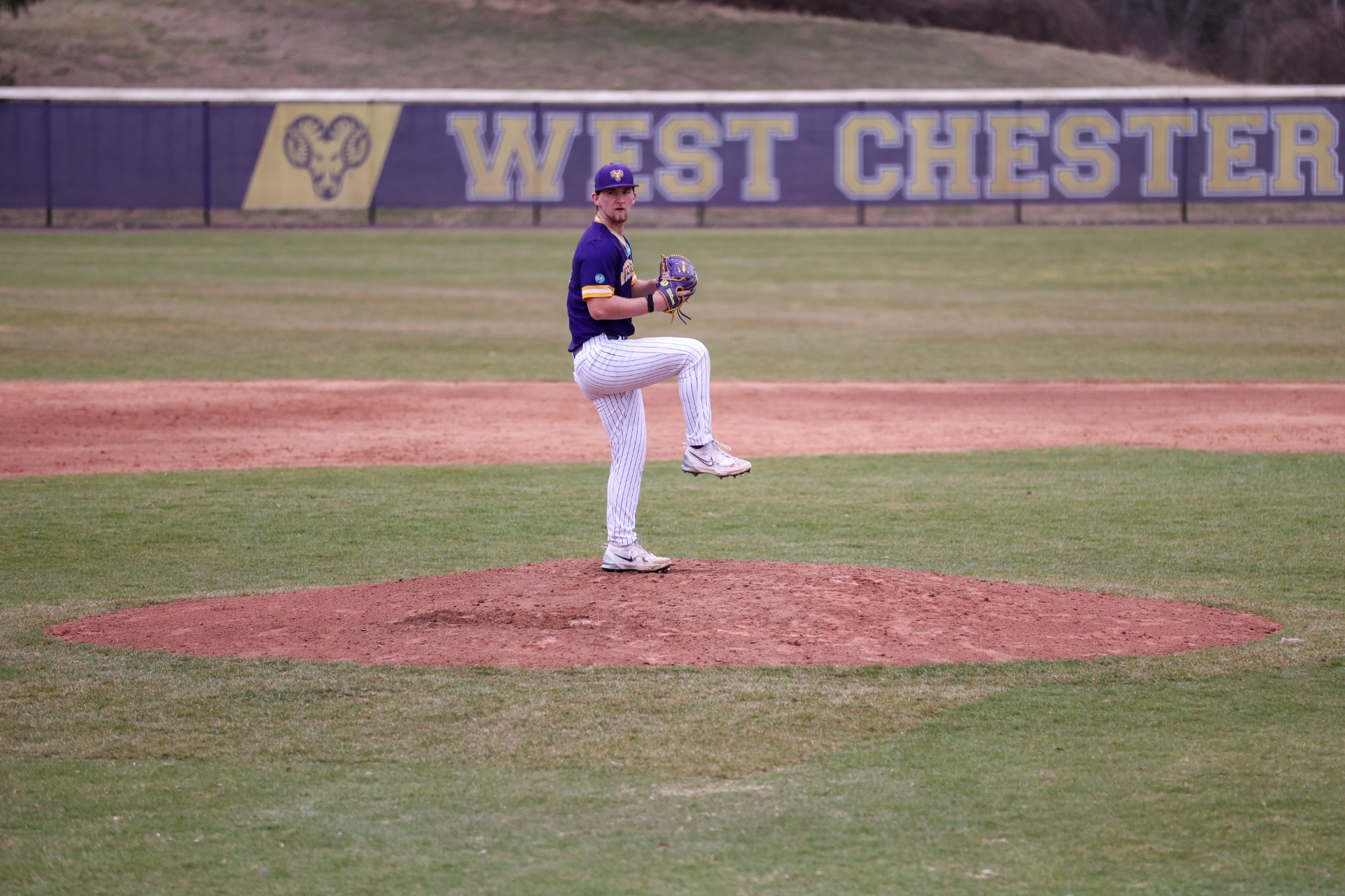Kyle Rogers pitches vs Gannon wearing Purple road top and white pinstripe pants