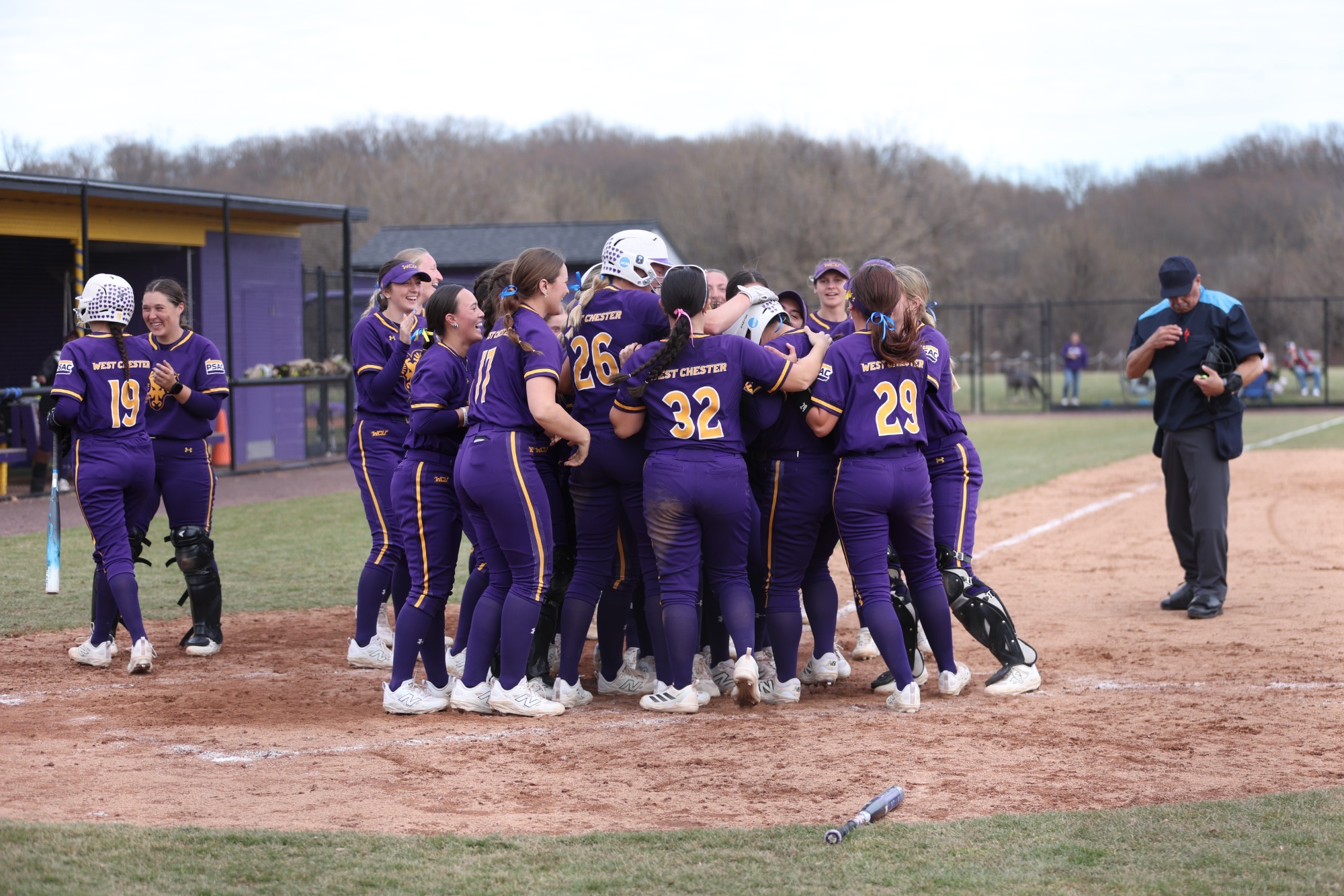 Softball team in new home purple uniforms celebrates a home run at the plate during doubleheader sweep of Lock Haven on Saturday