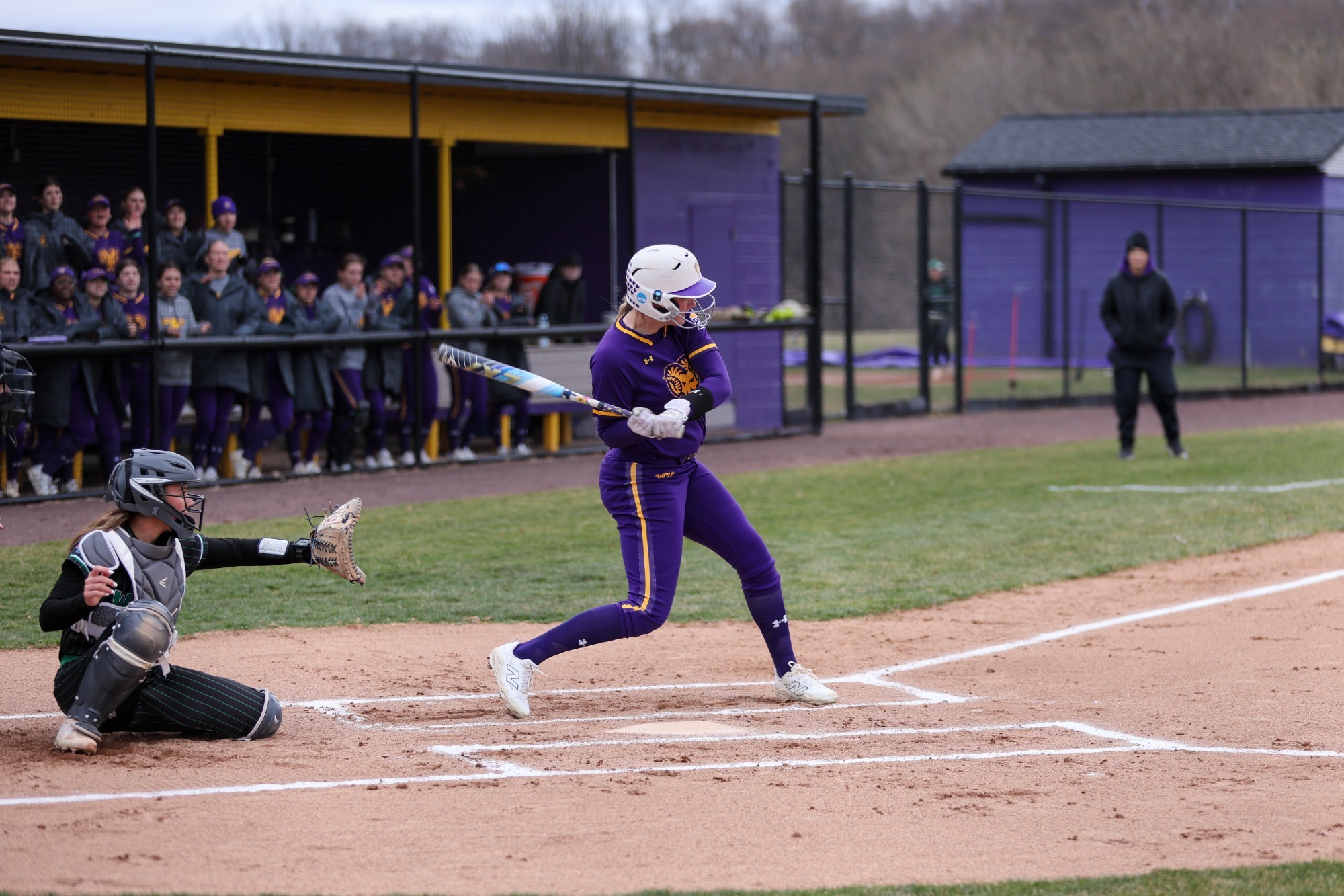 Mairead Hopkins swings vs Wilmington wearing all purple home uniforms on 3-15-26