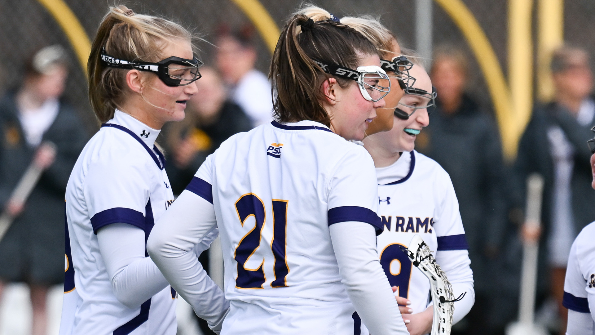 Marissa Herring, in her home white jersey with purple trim and purple number 21 with her back to the camera, Celebrates a WCU goal with Ava Sheeran and Kendall Fortune 