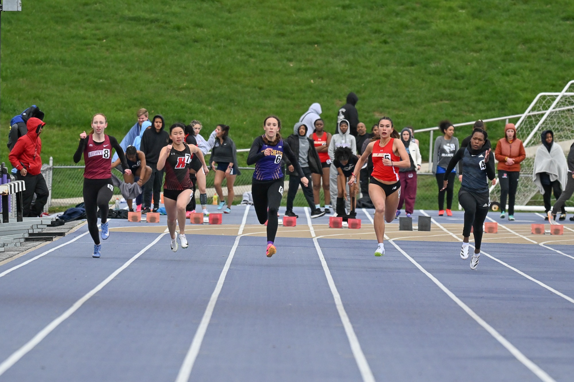 Ava Mills running in 100 in purple racing top and black pants at 2025 Bill Butler Invitational