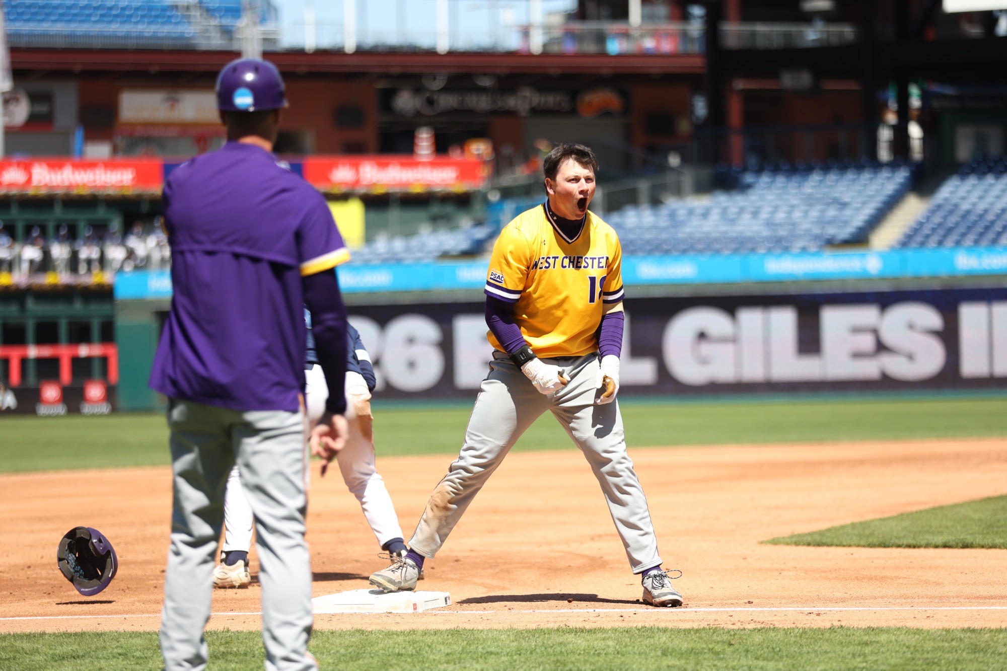 #18 Hunter Smith wearing yellow jersey and gray pants celebrates with a yell without his batting helmet after a bases-clearing triple at the Bill Giles Invitational on Tuesday