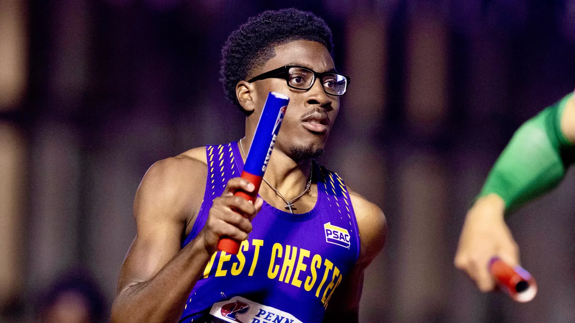 Xavier Jones carries the baton during the 4x400 at the Penn Relays in his purple track uniform