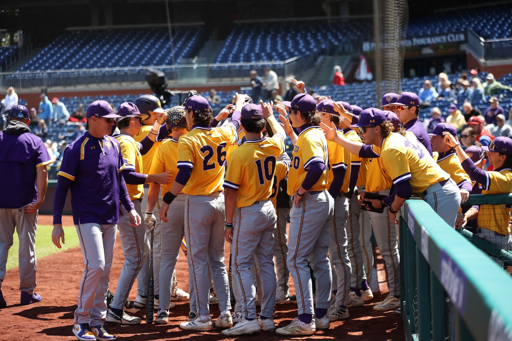 Baseball team wearing gold tops and gray pants huddles pregame on field at citizens bank park before Giles Classic game vs Jefferson
