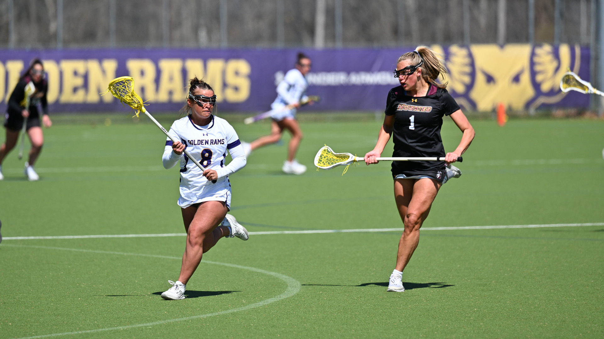 Gianna Booker raises up field past a Bloomsburg defender at Vonnie Gros Field in her home white jersey with purple numbers and letters outlined in gold