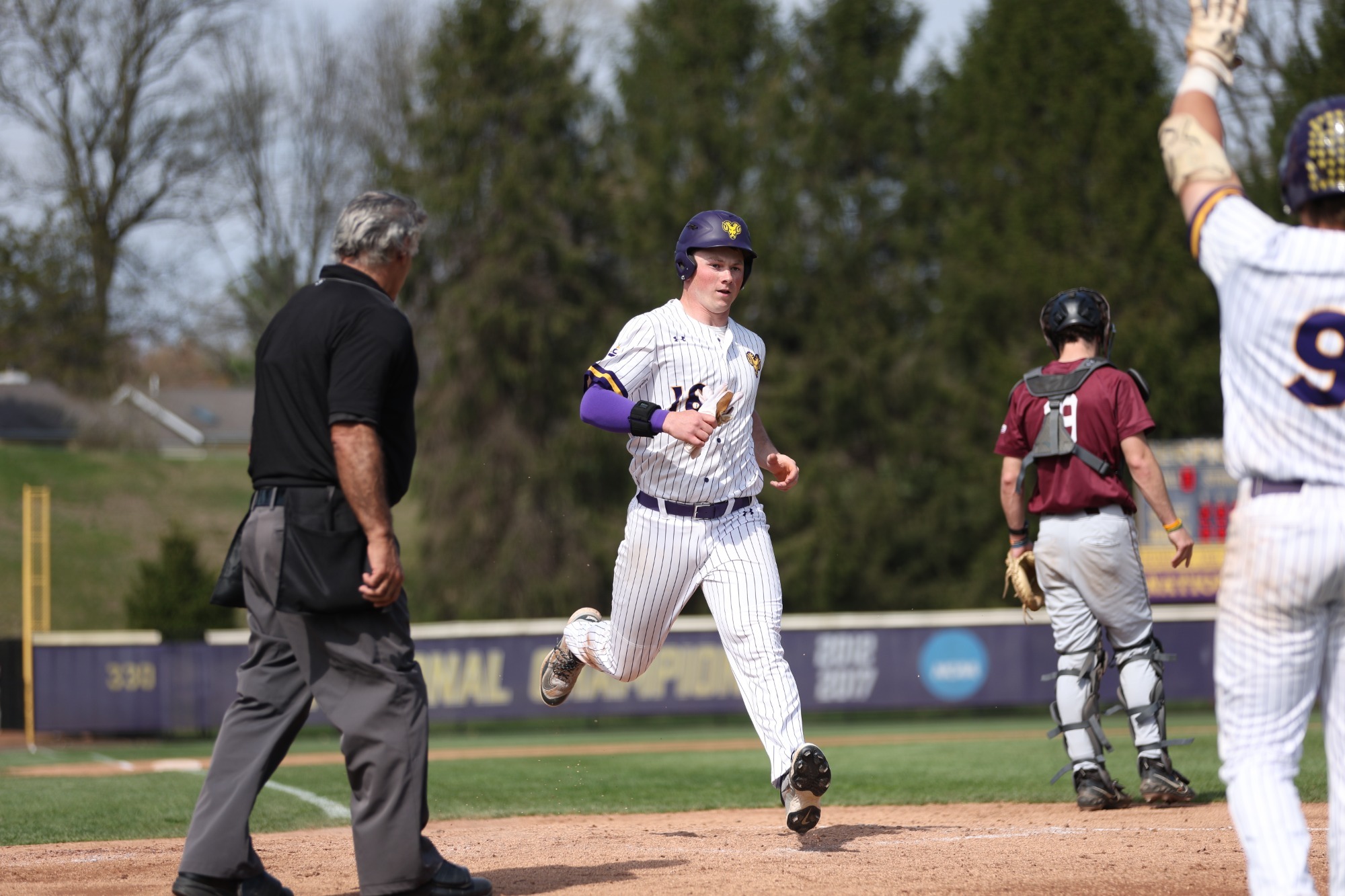 Hunter Smith crosses home plate vs Kutztown wearing home white uniform on 4-4-26
