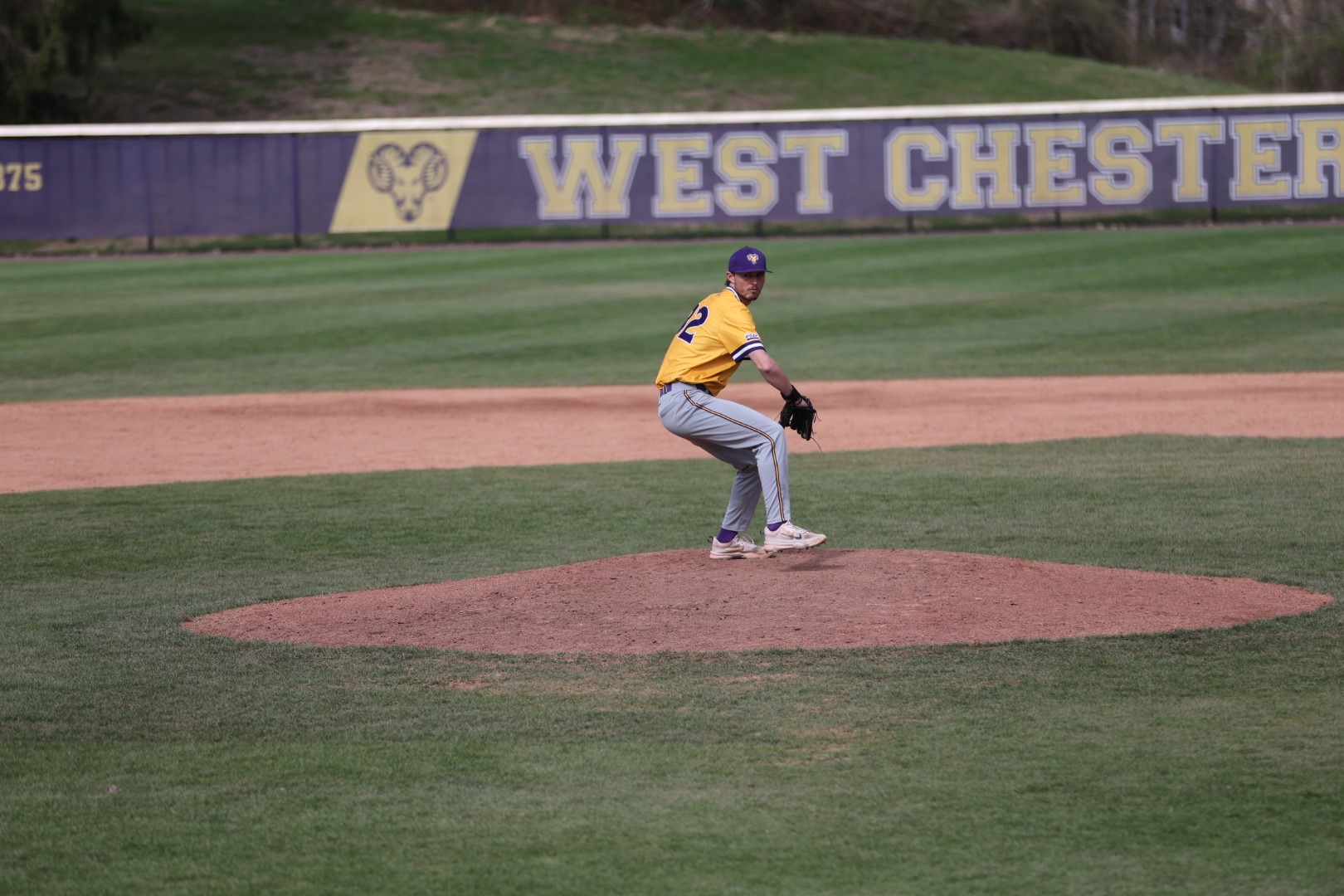 Ryan DeHaven pitching wearing new gold top and gray pants vs Chestnut Hill in Bill Giles Opening game on 4-6-26