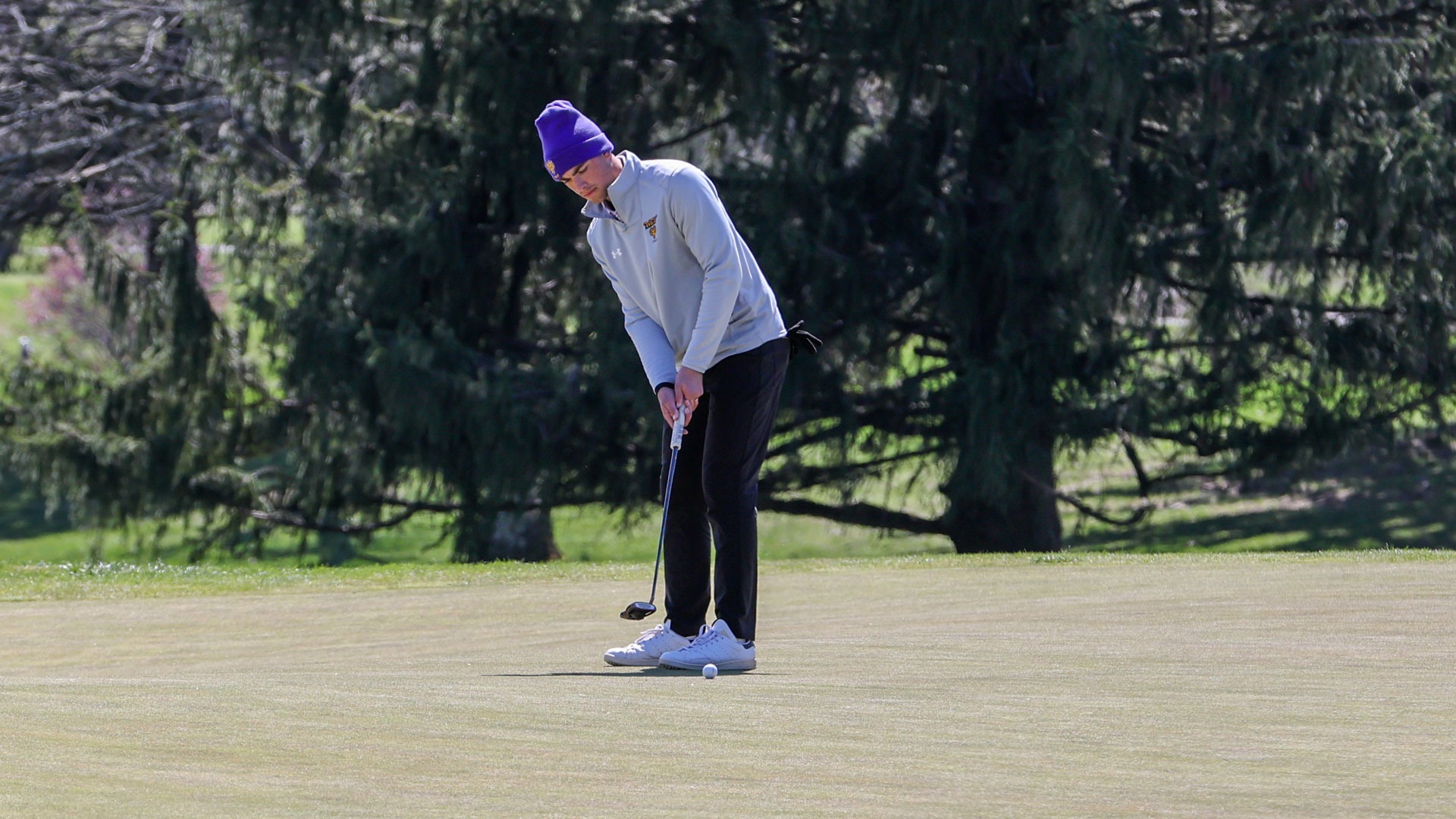 William Hilton hitting a putt on the fourth green wearing gray pullover, black pants, and purple wcu ski hat at Dr. Edwin B. Cottrell Invitational at Penn Oaks on Tuesday