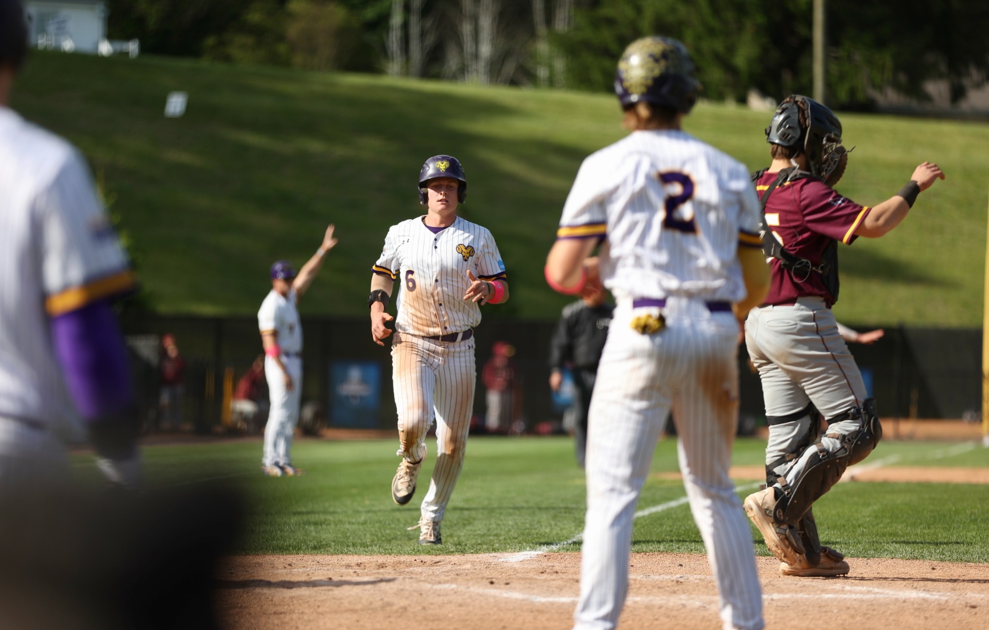 Drew Simpson wearing home white pinstripes running toward Caleb Strawhecker at home plate as he scoresa run vs Bloomsburg on 5-14-26 in NCAA Tournament
