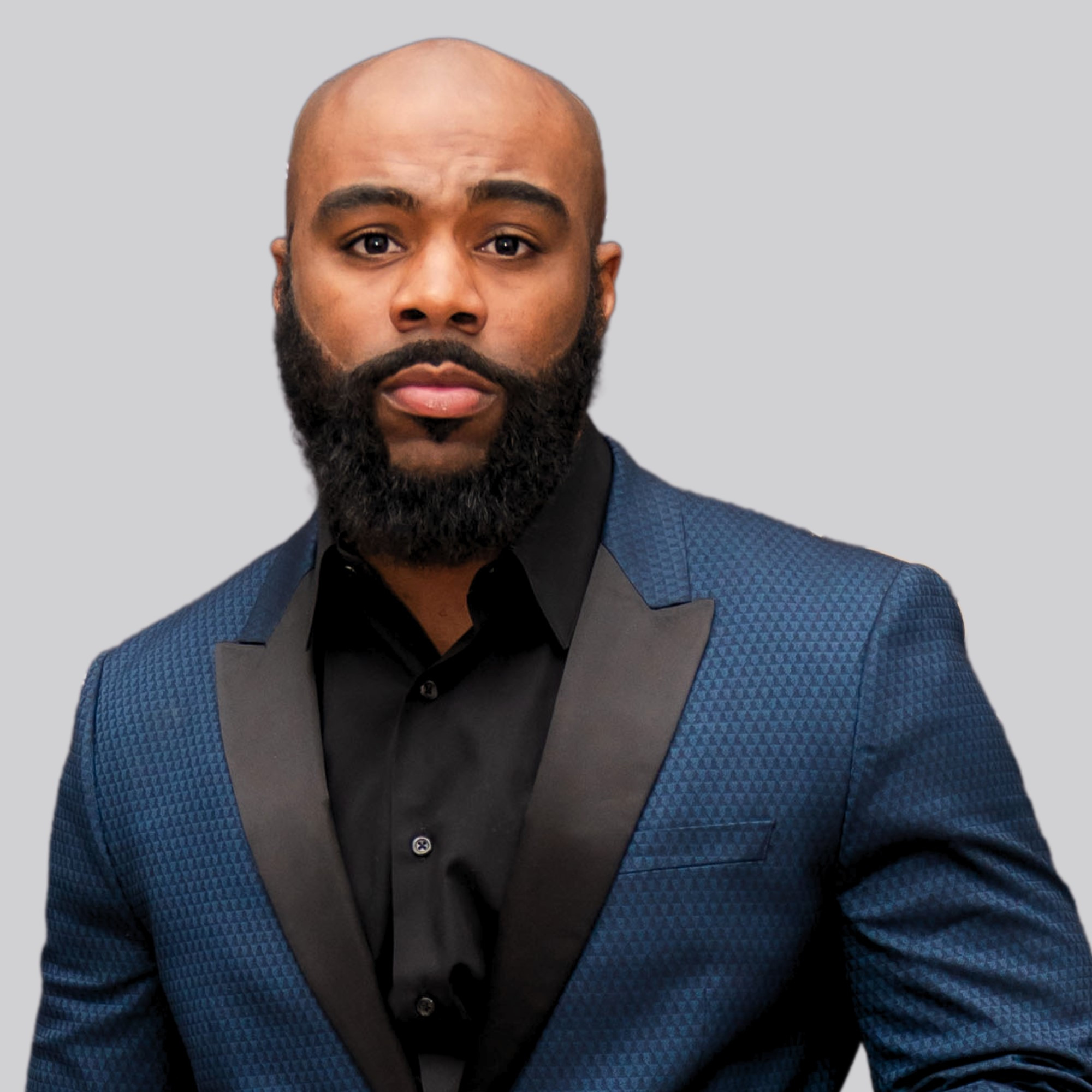 Rasheed Bailey head shot in black button-down shirt and blue blazer with black lapel